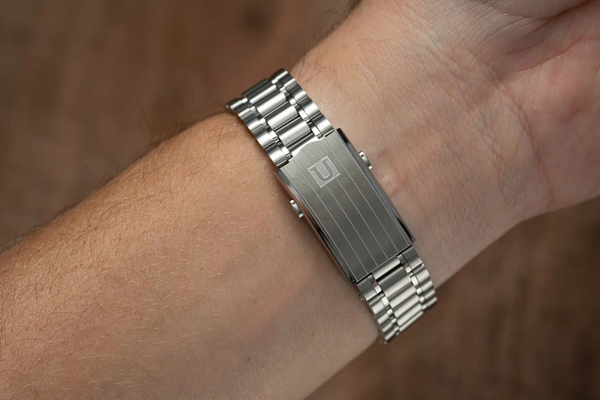 Silver stainless steel bracelet watch with polished rectangular case and metal band worn on wrist