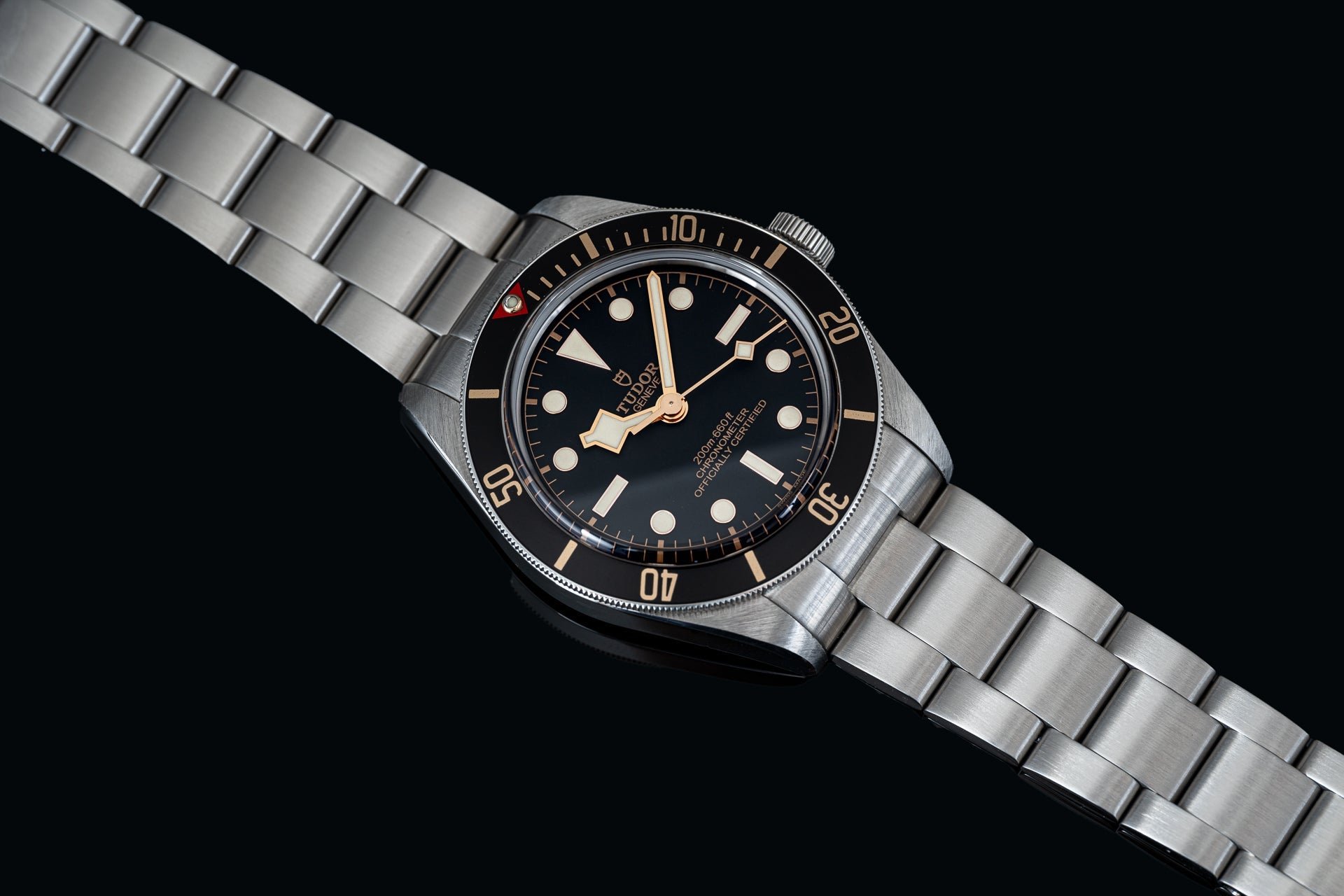 Vintage-style dive watch with stainless steel bracelet, black dial, luminous hour markers, and rotating bezel on black background