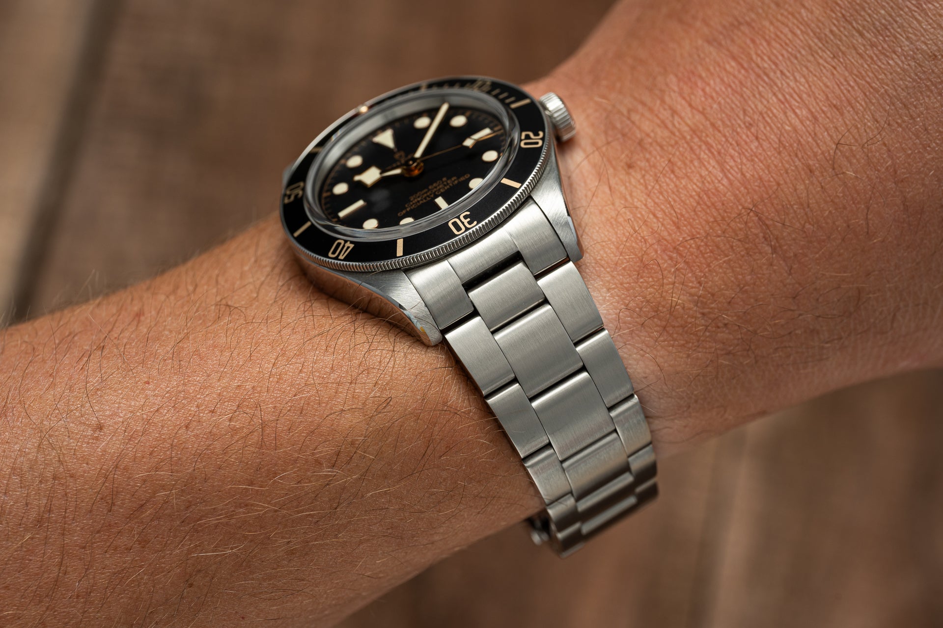 Stainless steel dive watch with black dial and bezel on matching metal bracelet, worn on wrist