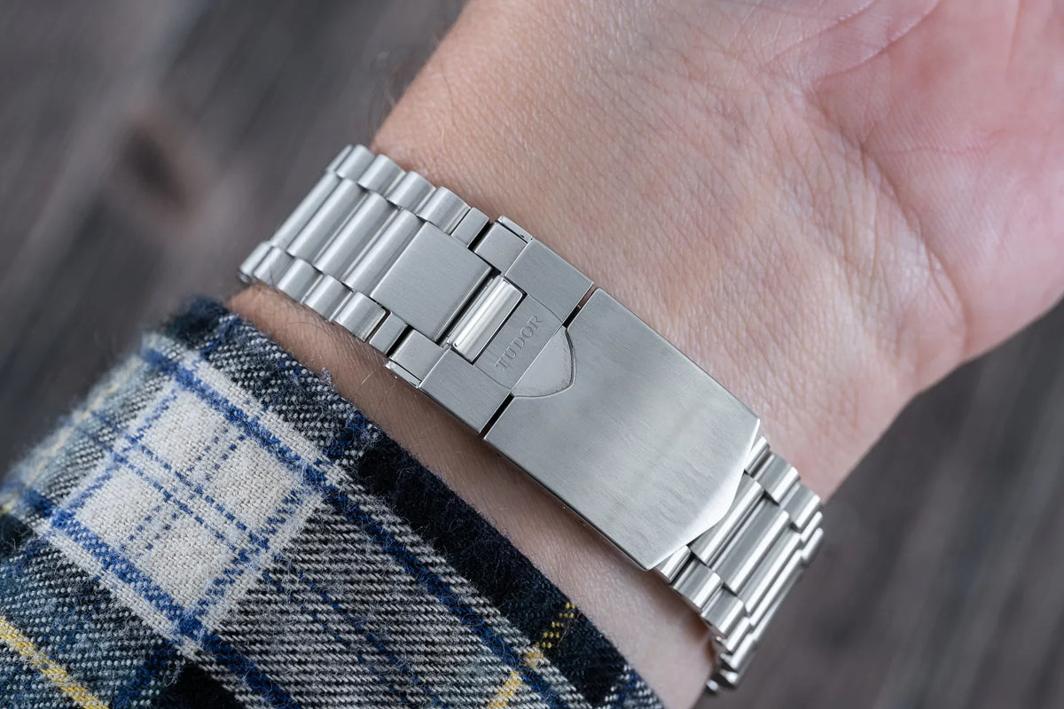 Stainless steel watch bracelet with solid links on wrist, featuring brushed and polished finish with integrated endlinks