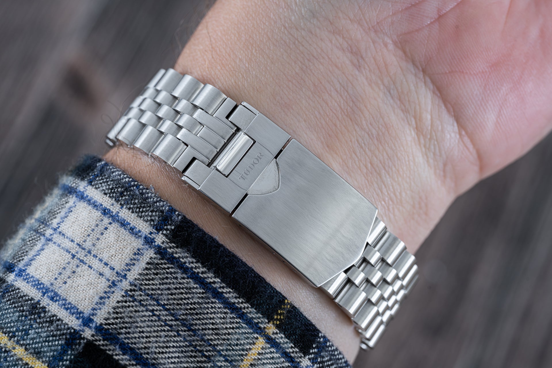 Stainless steel bracelet for Tudor 41mm watches with three-link construction worn on wrist with plaid fabric sleeve