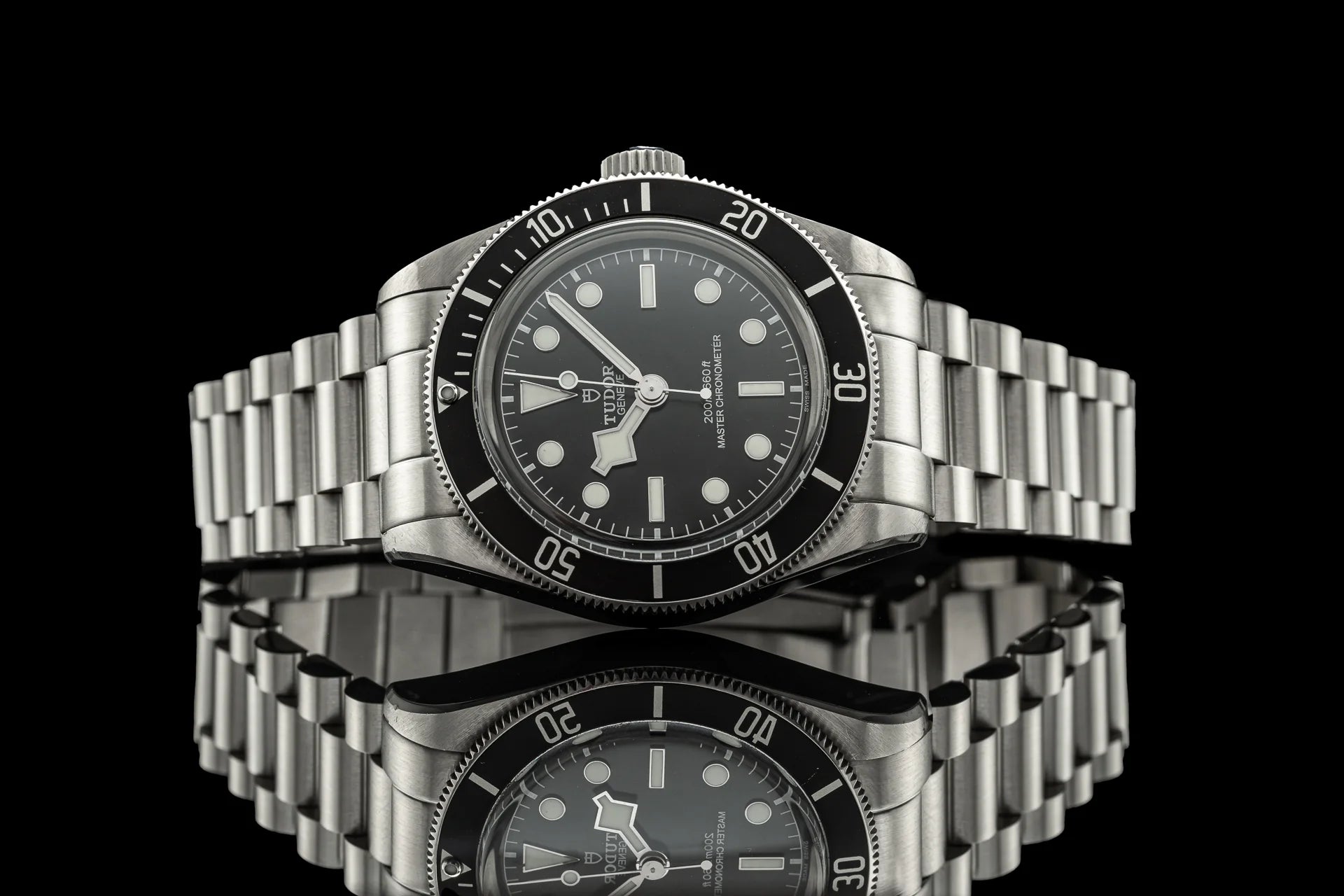 Stainless steel bracelet watch with black dial, rotating bezel, and metal link band on black background