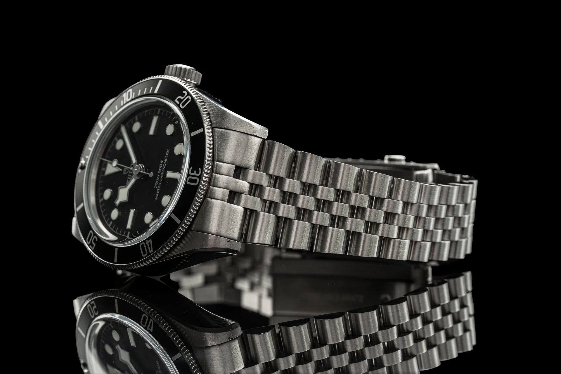 Stainless steel dive watch with black dial, rotating bezel, and matching steel bracelet on black background