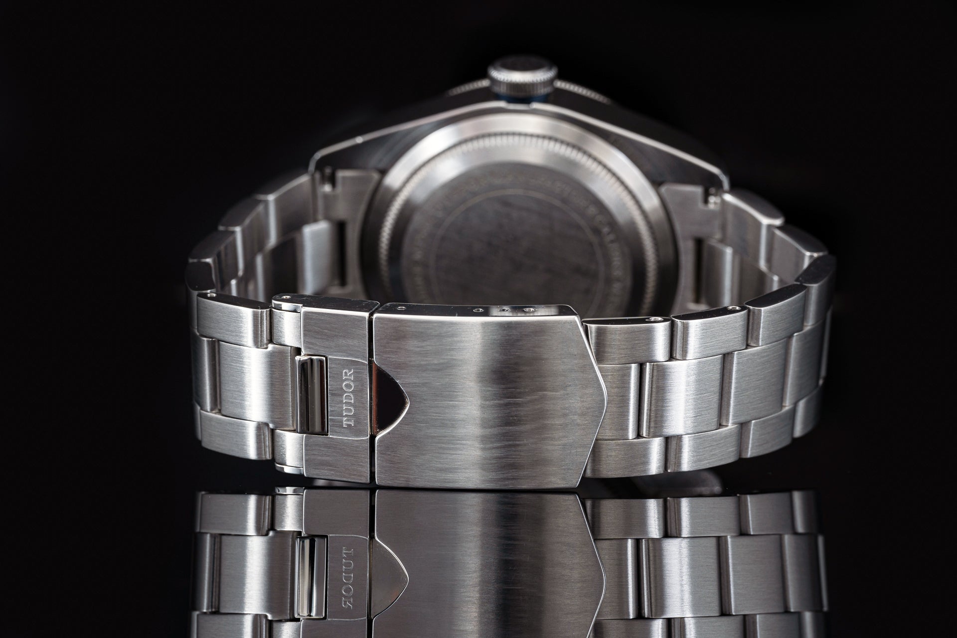 Stainless steel watch bracelet with integrated clasp for Tudor 41mm models, rear view on black background