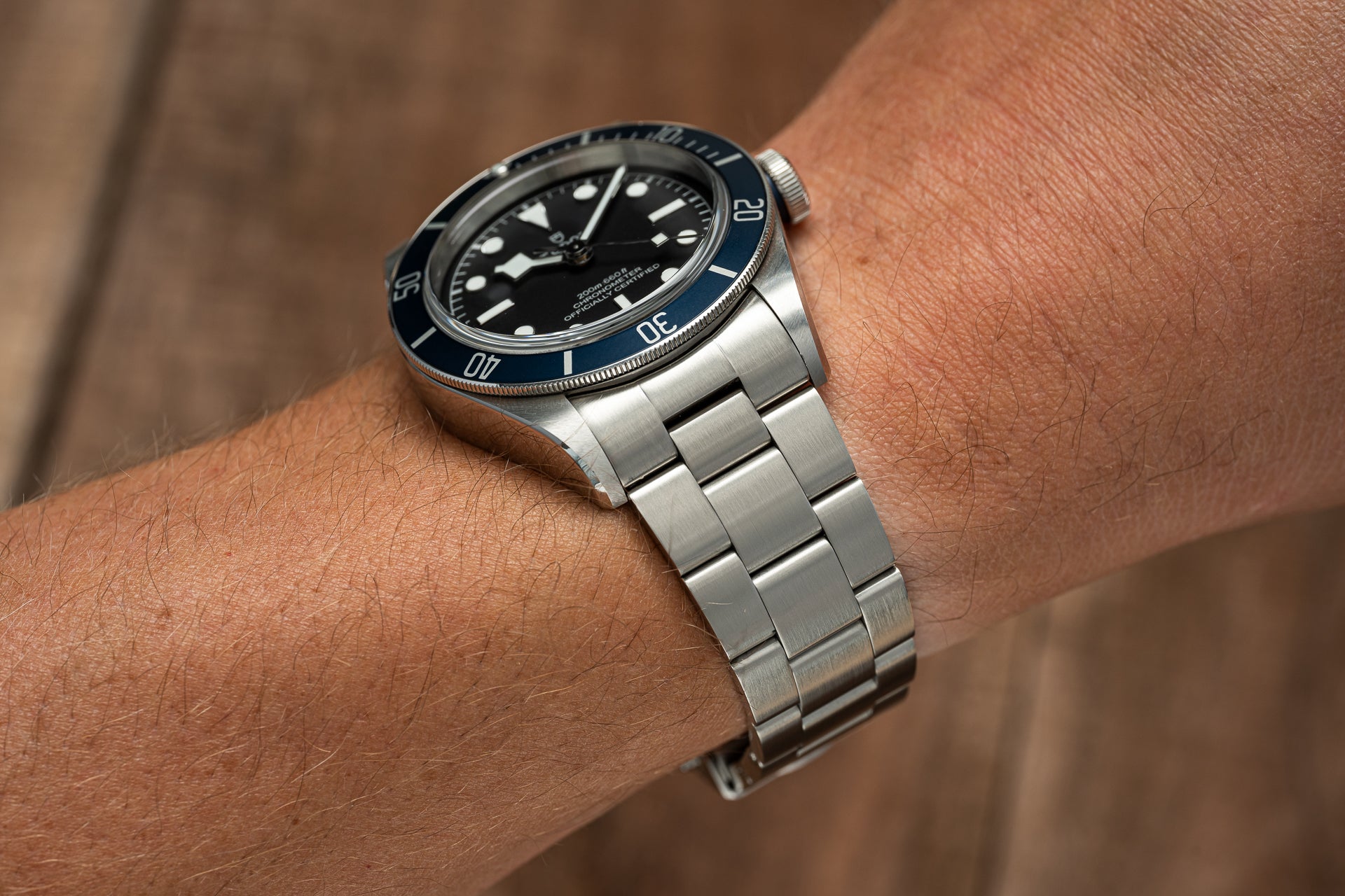 Stainless steel bracelet with three-link design fitted on Tudor 41mm watch with black dial and blue bezel