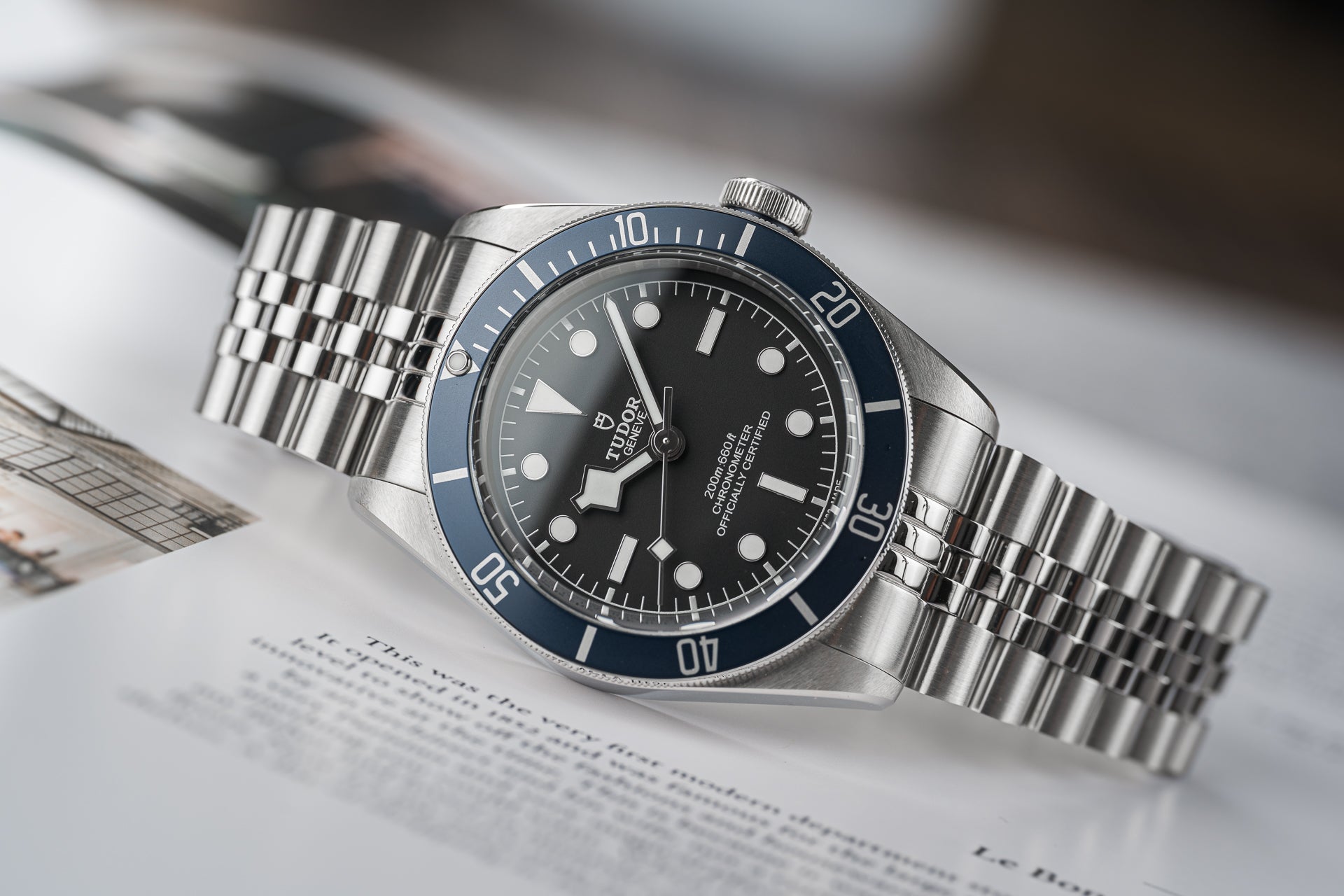 Tudor dive watch with stainless steel bracelet and blue bezel on technical document background