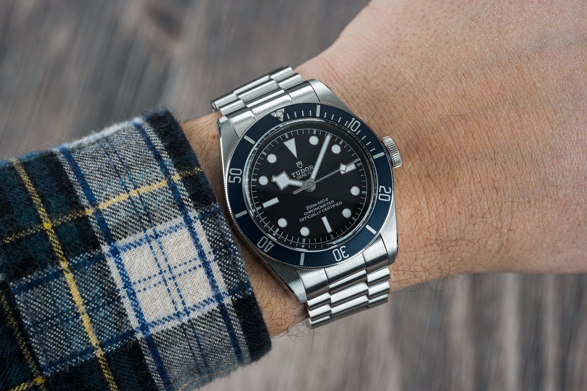 Tudor Black Bay 41mm stainless steel dive watch with black dial on Uncle US1450 Lincoln bracelet worn on wrist with plaid shirt