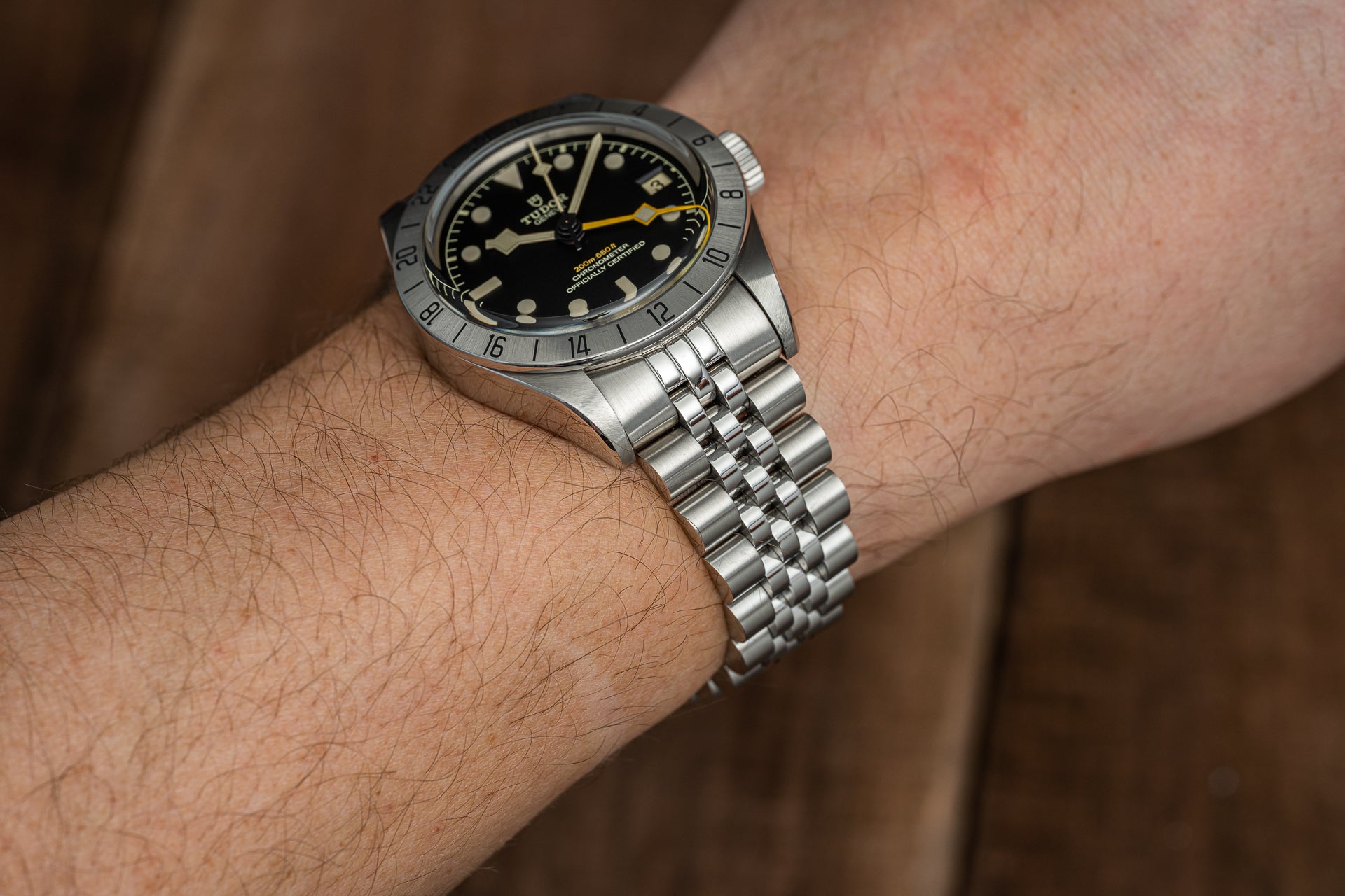Stainless steel bracelet with solid links fitted on Tudor Black Bay Pro watch with black dial and yellow hands on wrist