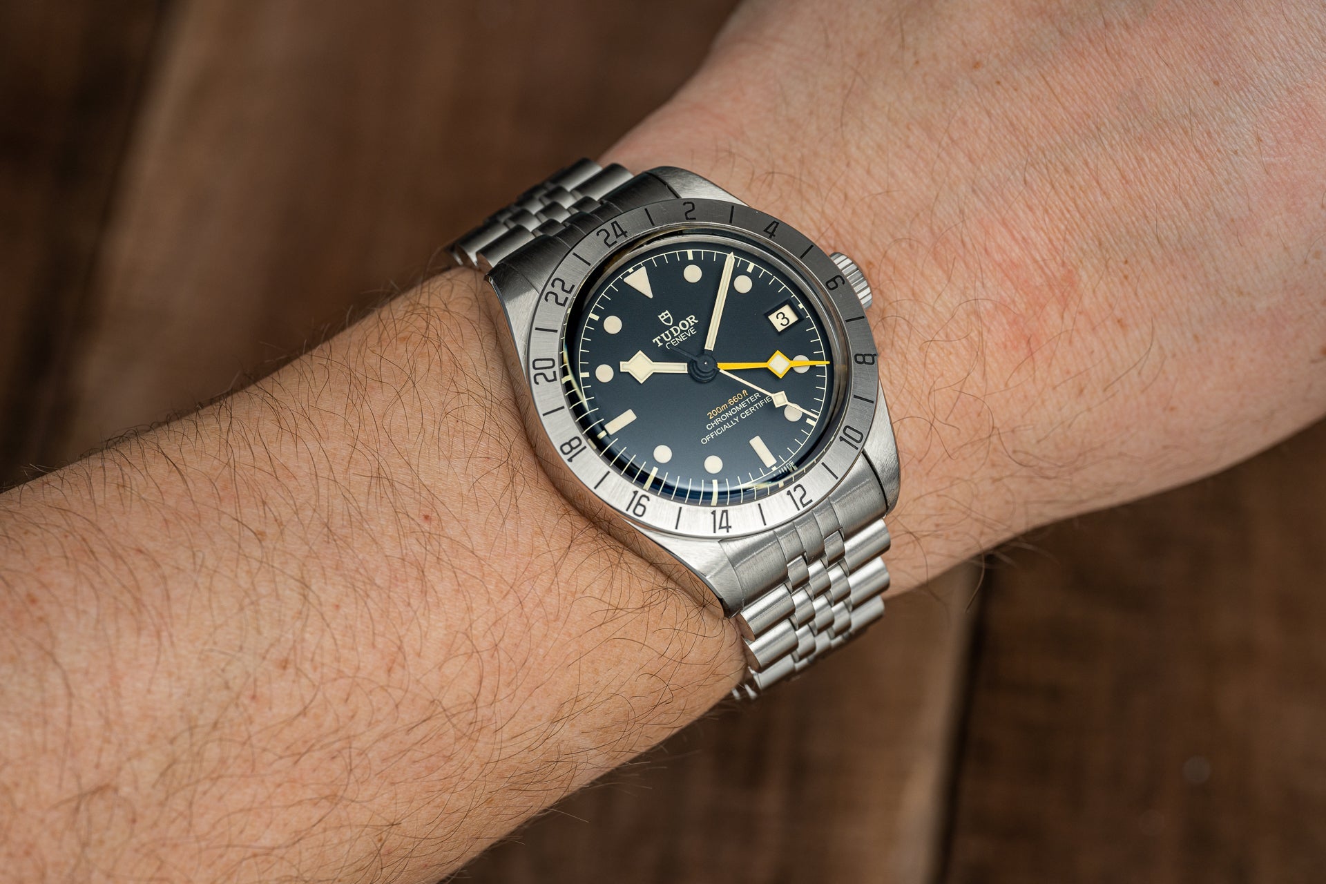 Stainless steel dive watch with black dial, luminous markers, date window, and GMT bezel on wrist