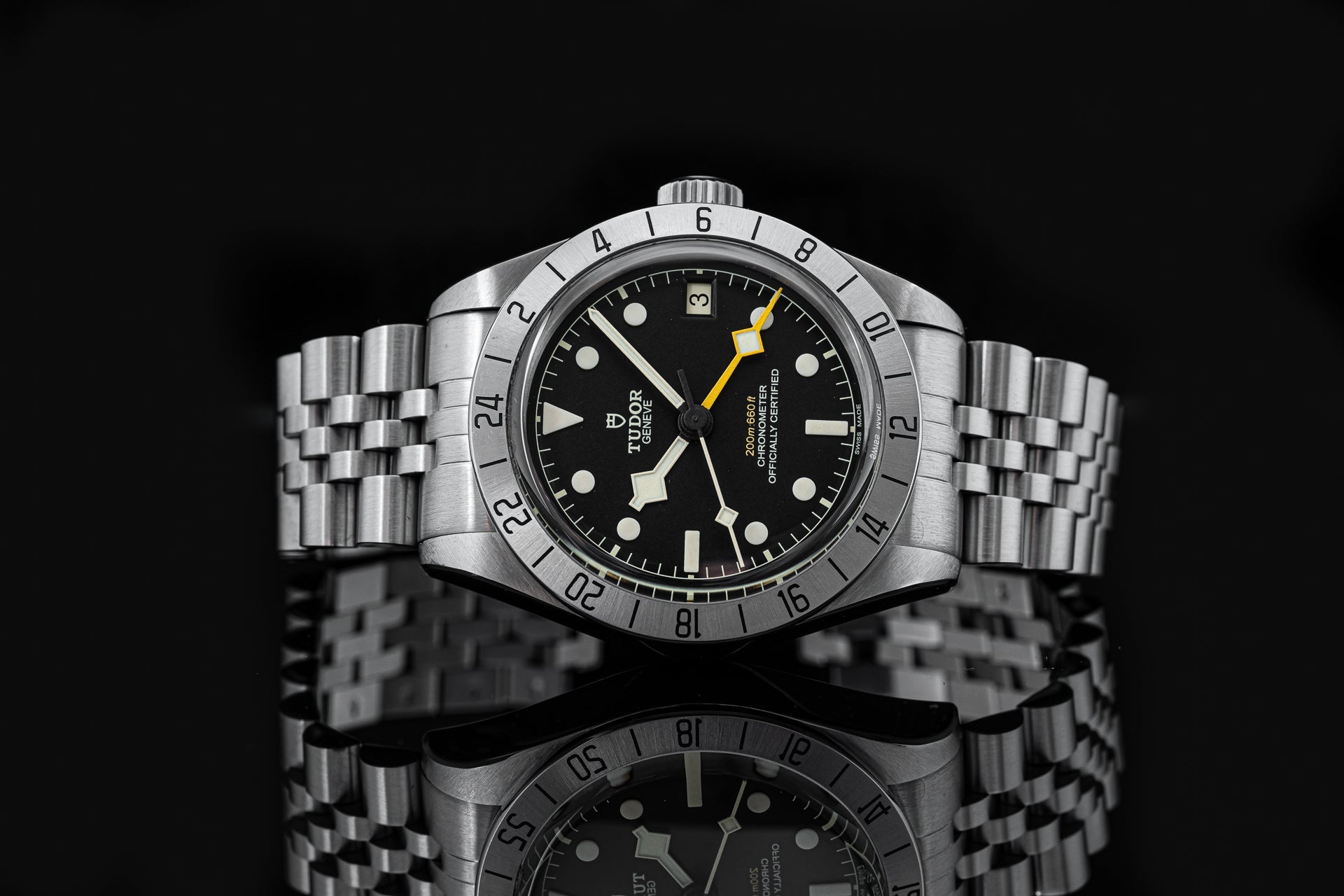 Tudor Black Bay Pro stainless steel dive watch with yellow hands, rotating bezel, and jubilee bracelet on black background