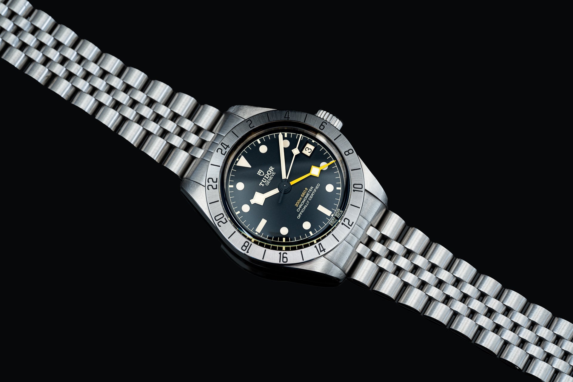 Stainless steel dive watch with black dial, luminous hands, yellow accents, rotating bezel, and matching metal bracelet on black background