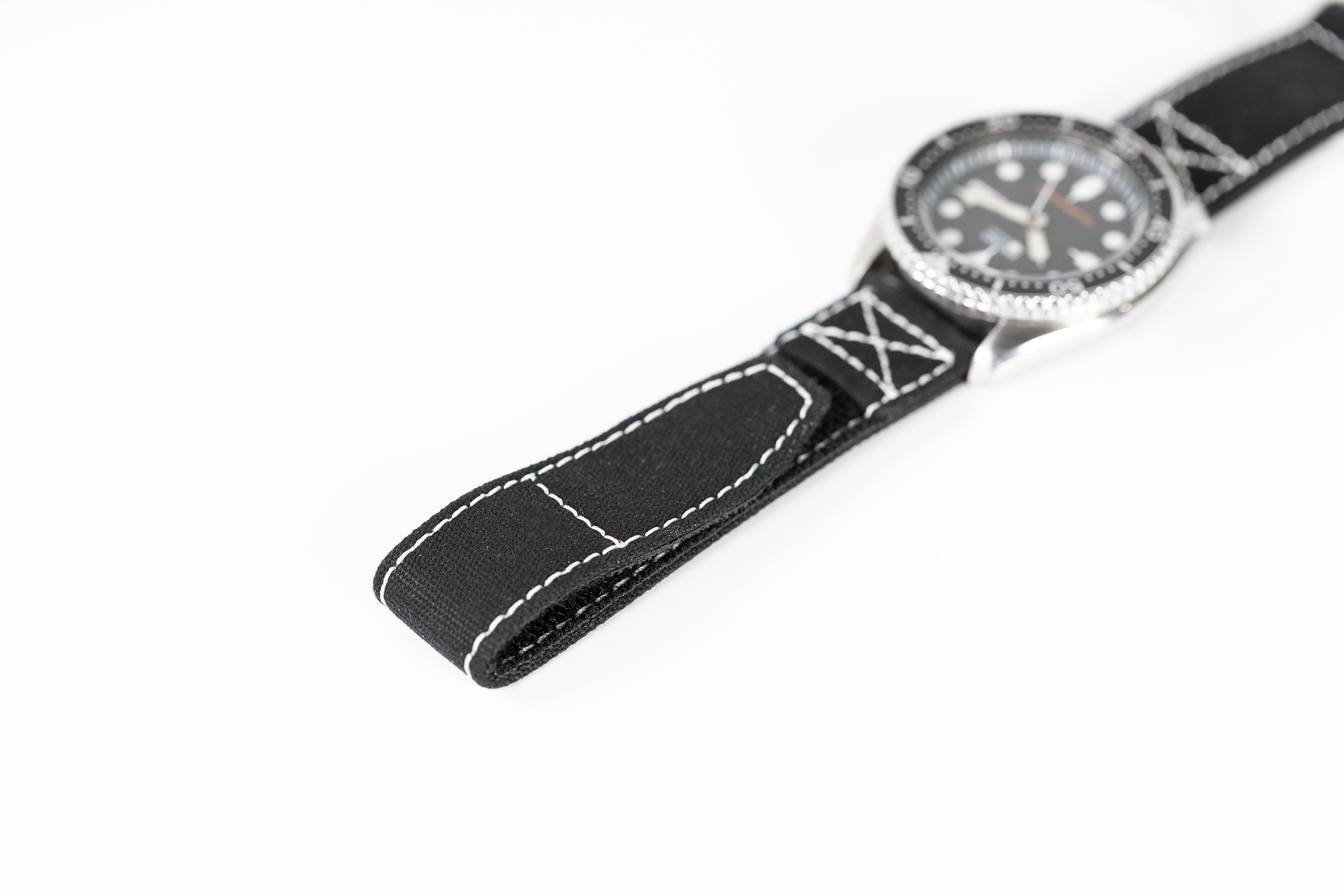 Military dive watch with black quick release strap featuring white contrast stitching and rotating bezel