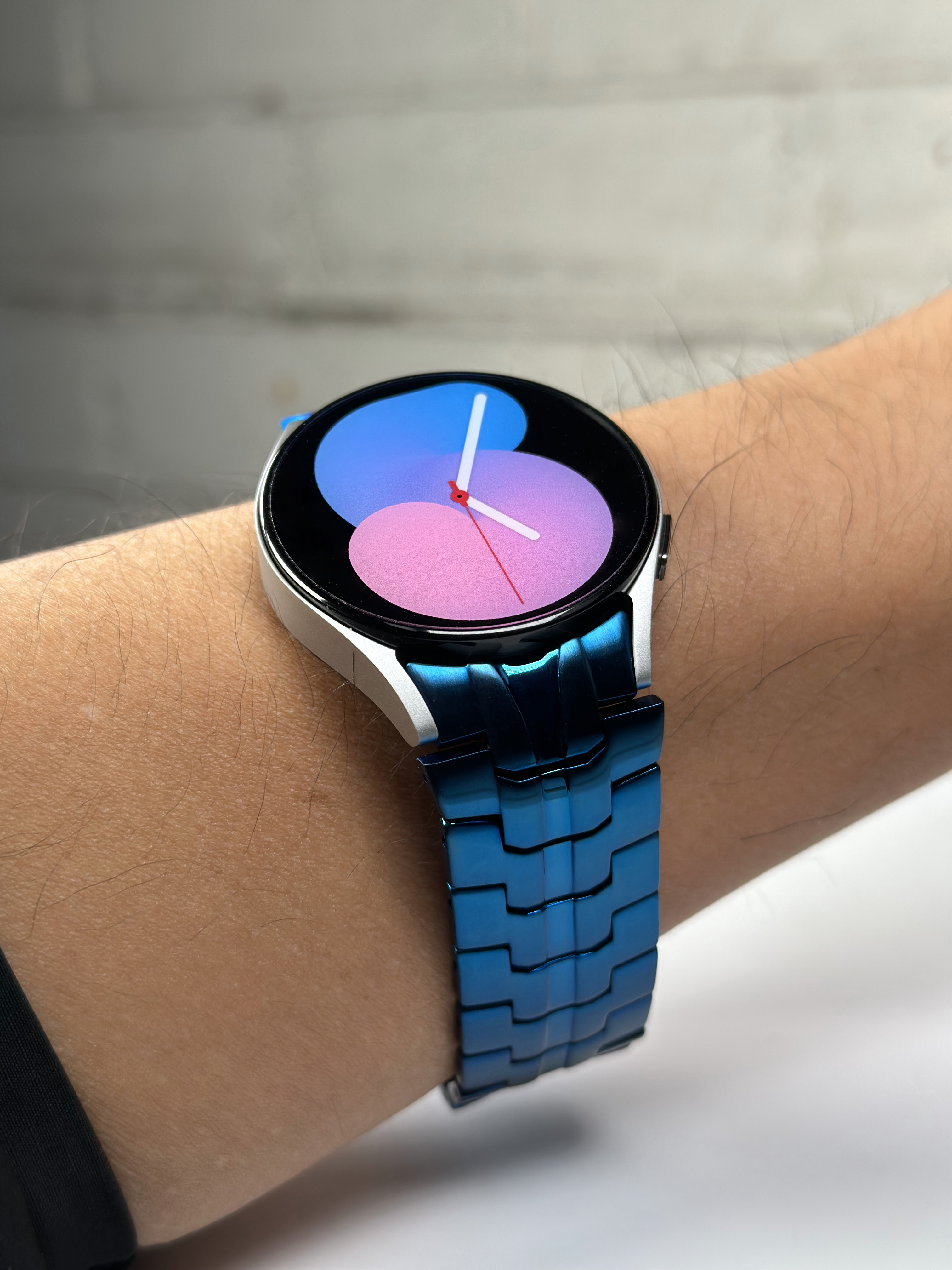 Samsung Galaxy Watch smartwatch with blue steel link bracelet displaying colorful gradient watch face on wrist
