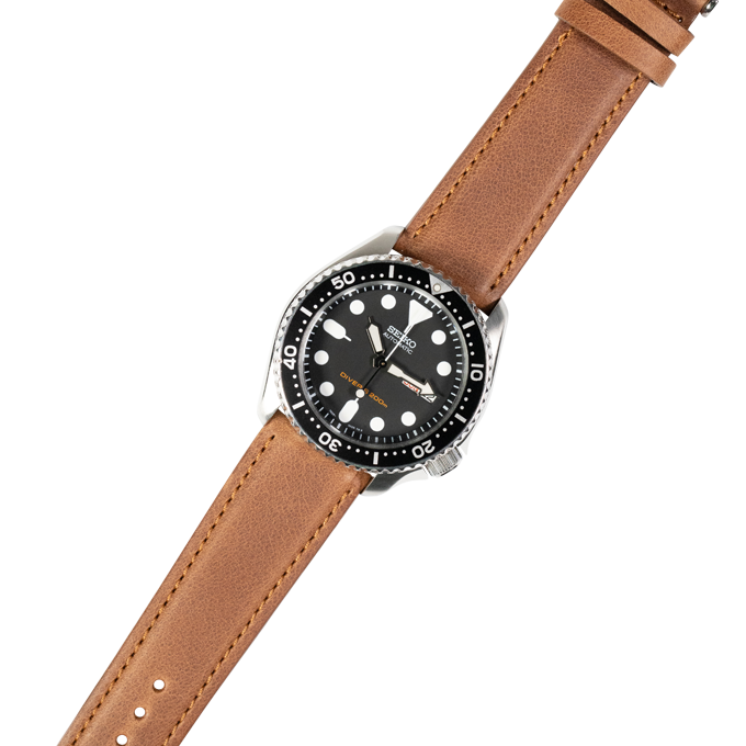 Stainless steel dive watch with black dial and tan leather quick release strap with white stitching