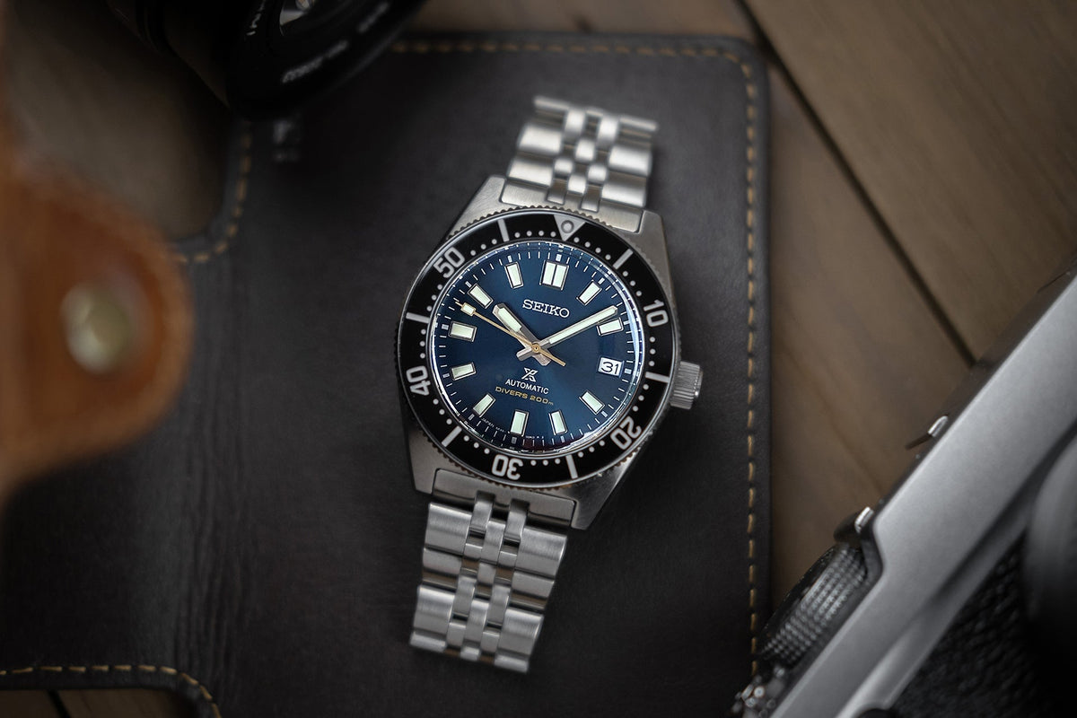 Seiko automatic dive watch with blue dial, stainless steel bracelet and black bezel on leather background