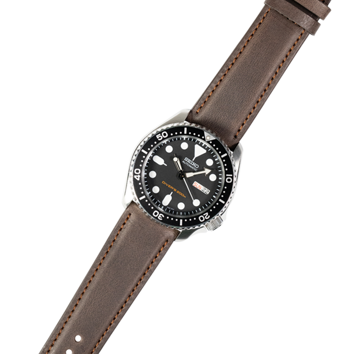 Dive watch with black dial and rotating bezel on brown leather strap with stitched edges