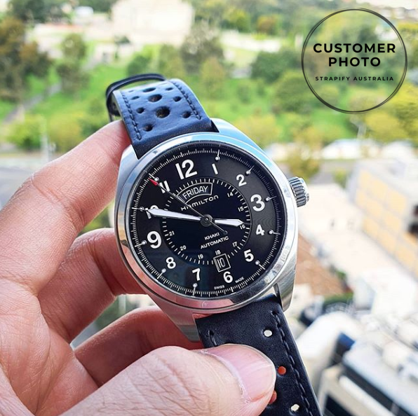 Hamilton Khaki Field automatic watch with black dial and leather strap held in hand outdoors