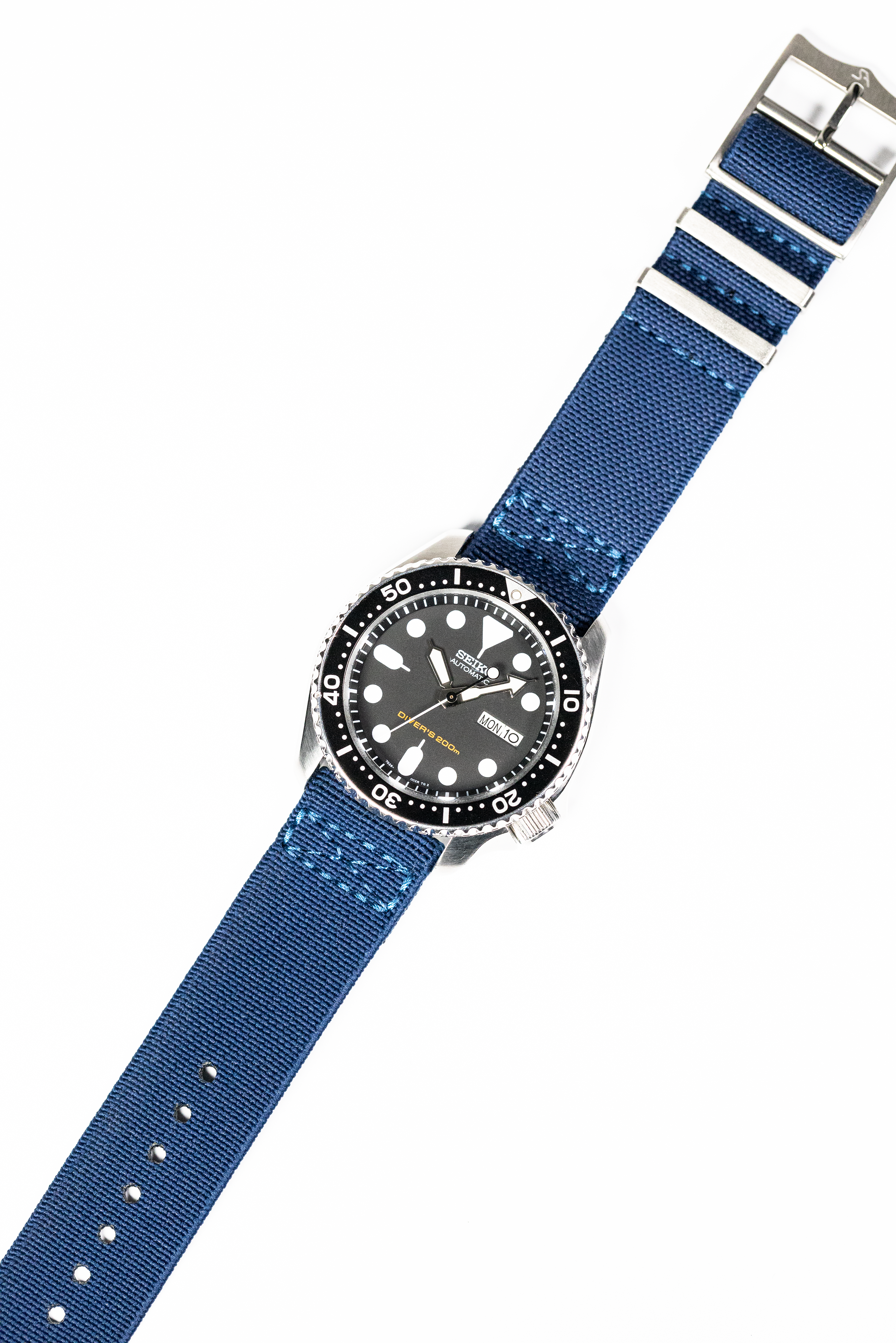 Seiko automatic dive watch with black dial, rotating bezel, and blue fabric military-style strap with white stripes