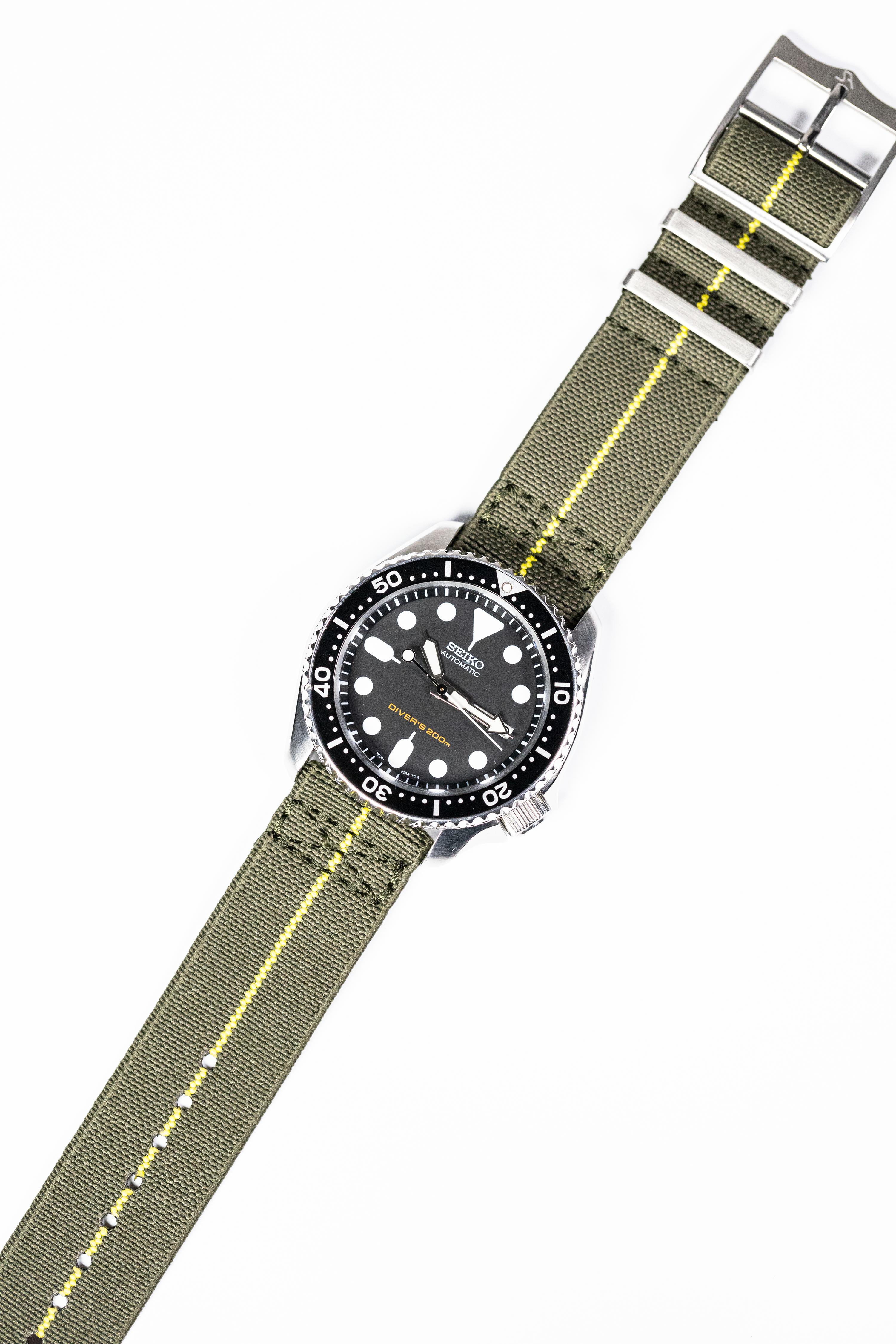 Seiko dive watch with black dial and olive green fabric strap featuring yellow stripe and quick release buckle