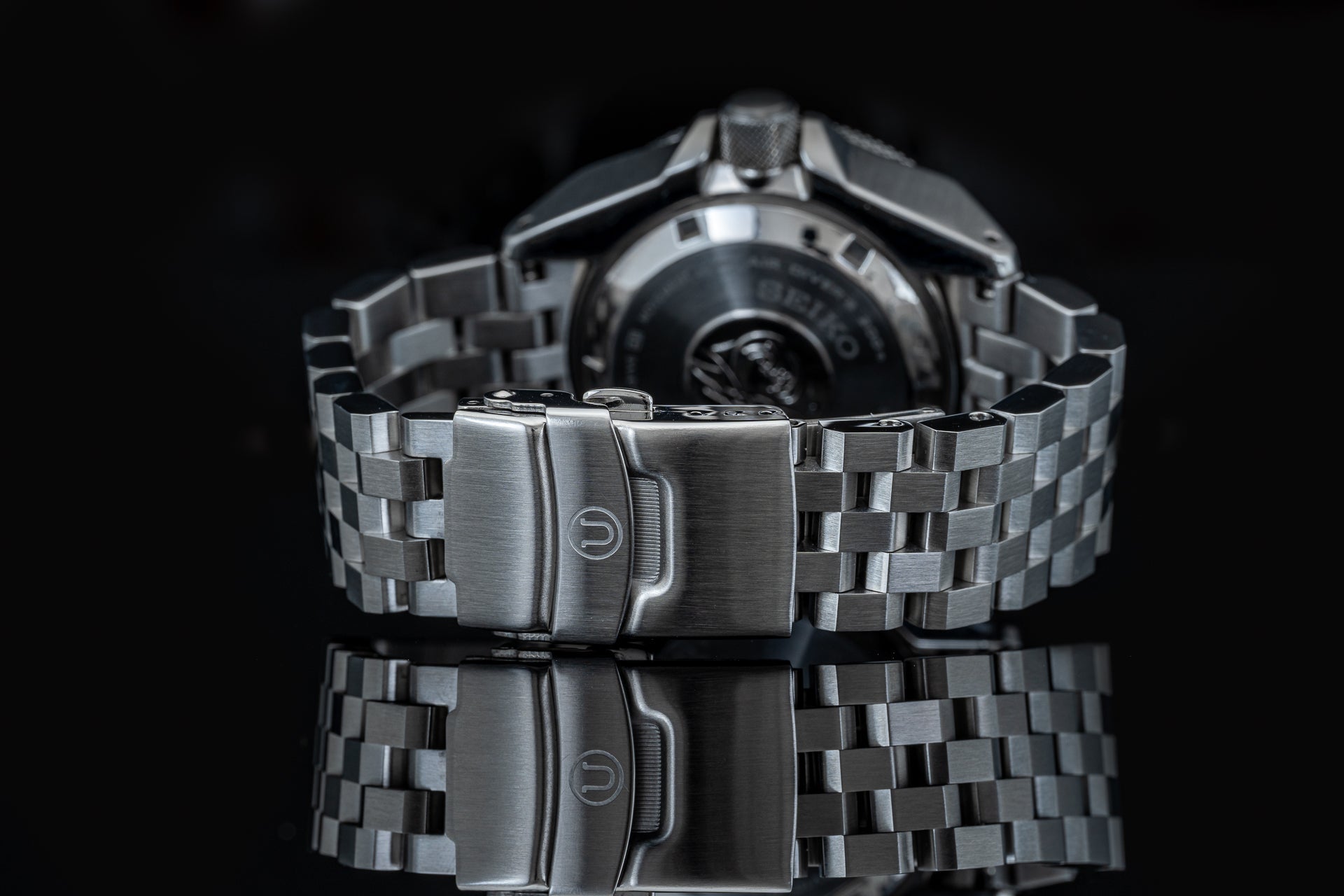 Stainless steel bracelet with fold-over clasp for Seiko Samurai dive watch, rear view on black background