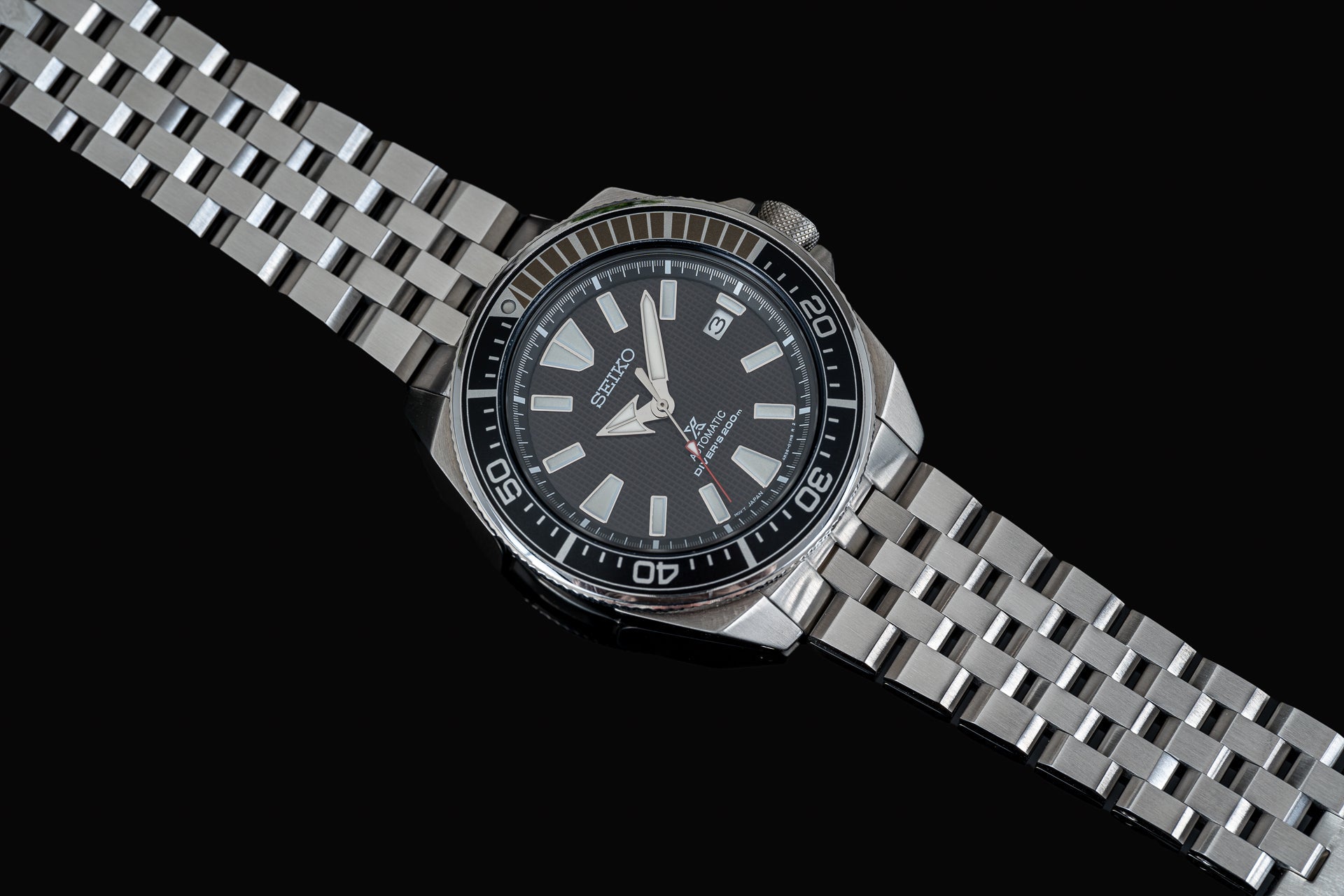 Seiko Samurai dive watch with black dial, stainless steel bracelet and bezel on black background