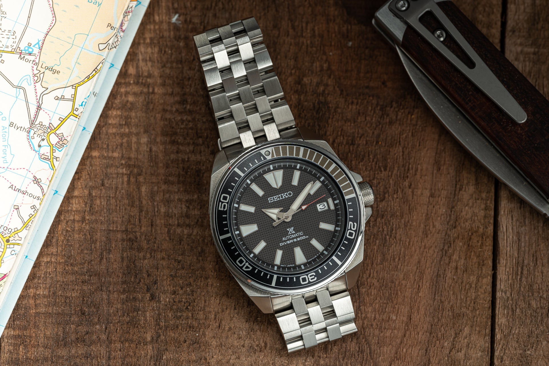 Seiko Samurai automatic diver's watch with stainless steel bracelet on wooden surface next to map