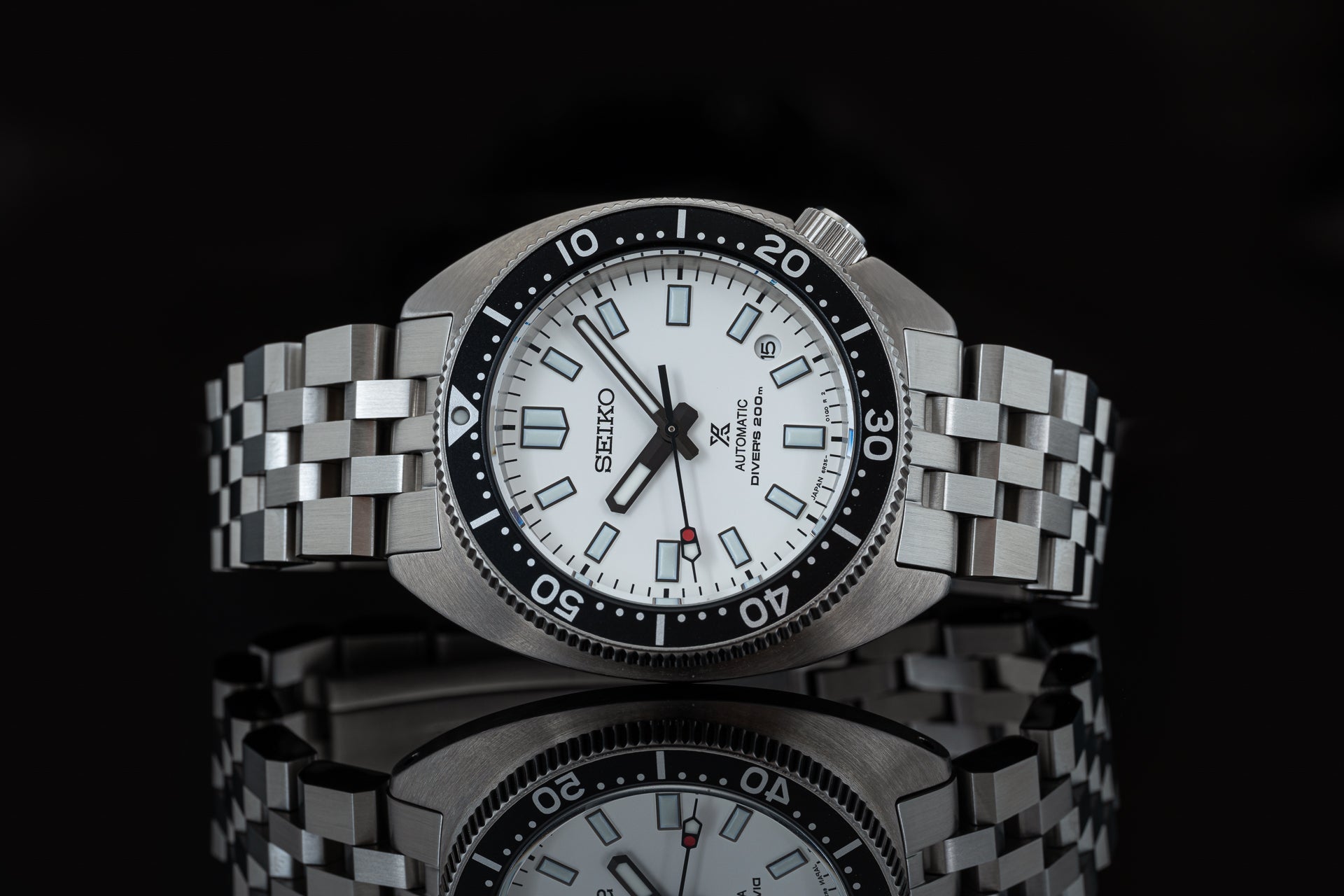 Seiko Super Engineer automatic dive watch with white dial, black bezel, and steel bracelet on black background