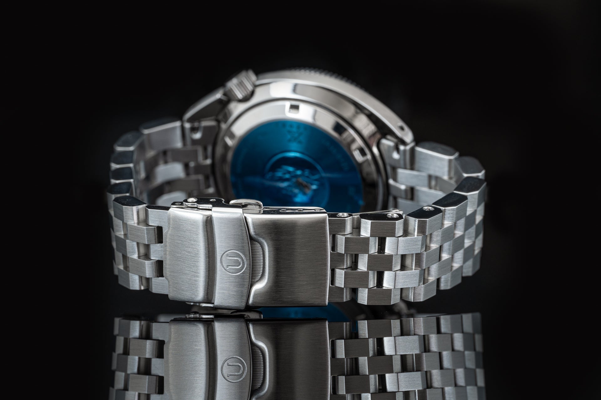 Stainless steel bracelet on Seiko SPB317 Slim Turtle dive watch with blue dial, displayed against black background with reflection