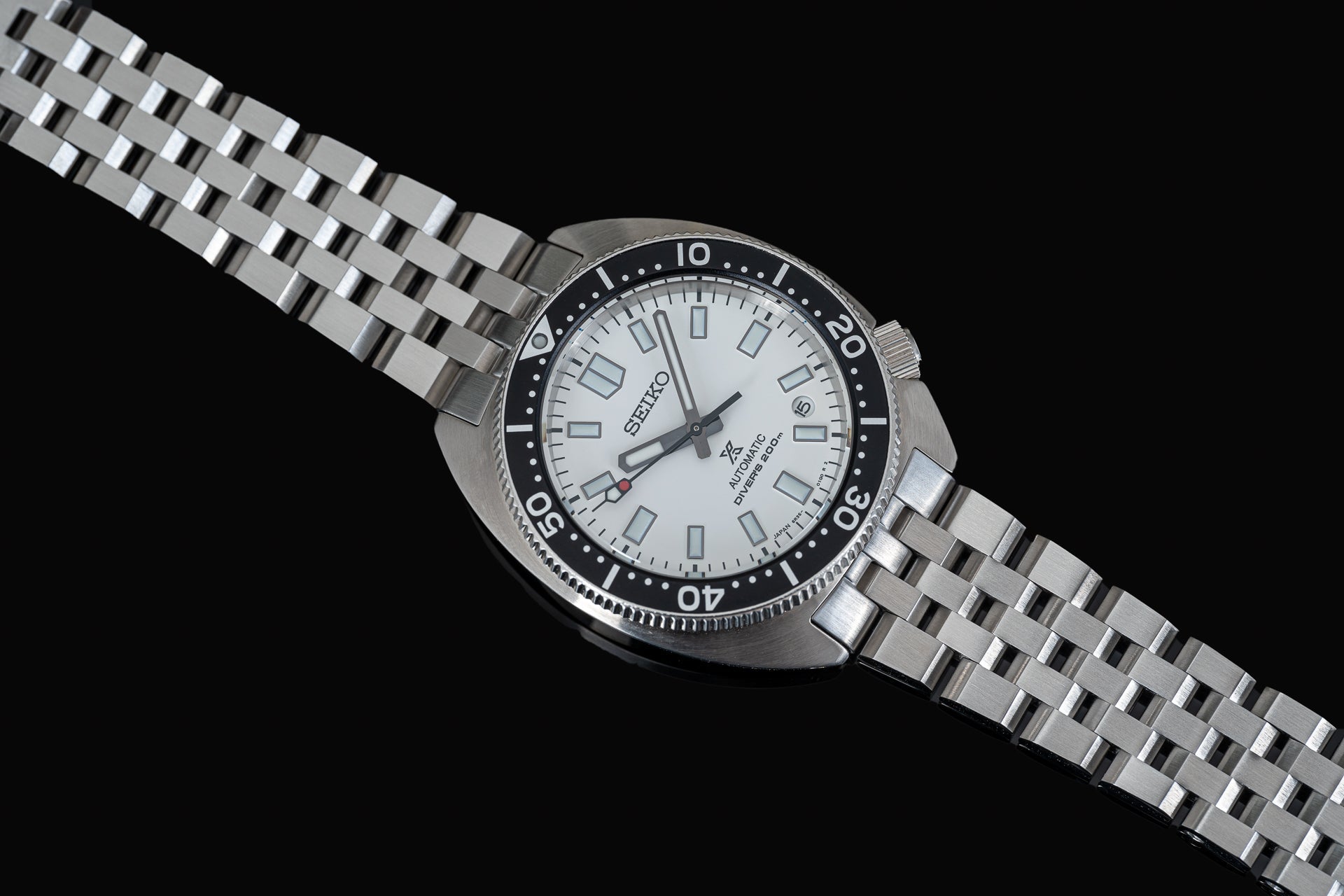 Seiko SPB317 Slim Turtle automatic dive watch with white dial, black bezel, and stainless steel bracelet on black background