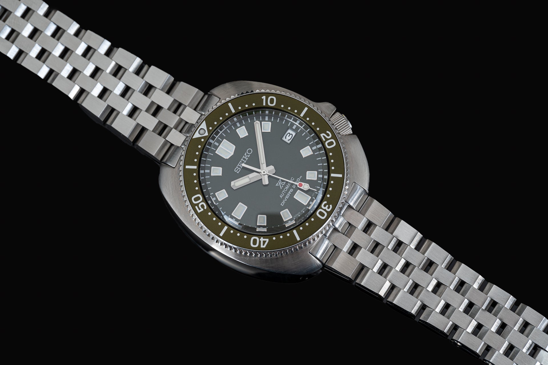 Seiko Super Engineer diving watch with olive bezel, black dial, and stainless steel bracelet on black background