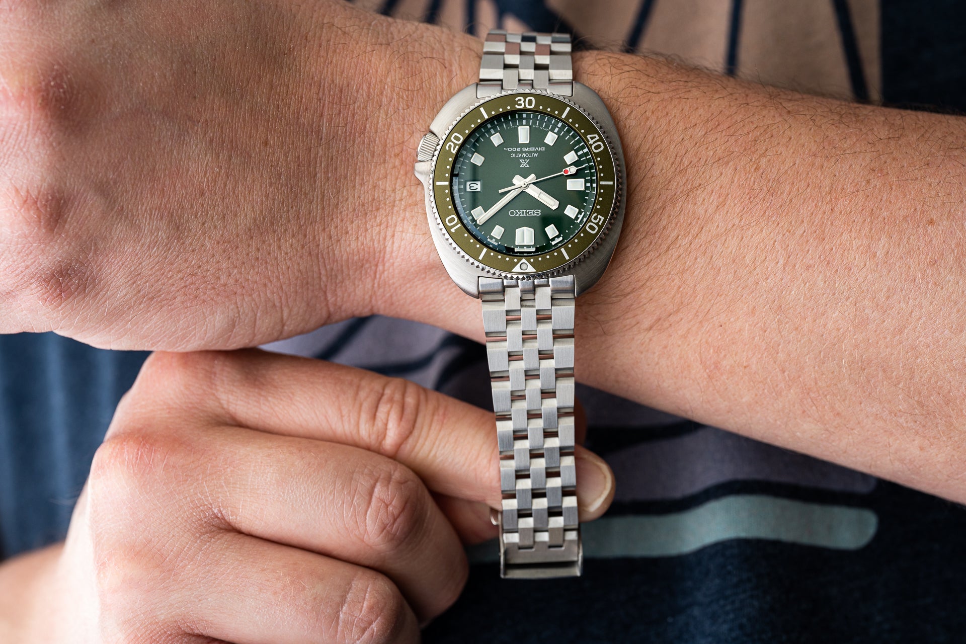 Seiko Prospex dive watch with green dial and olive bezel on stainless steel jubilee bracelet worn on wrist