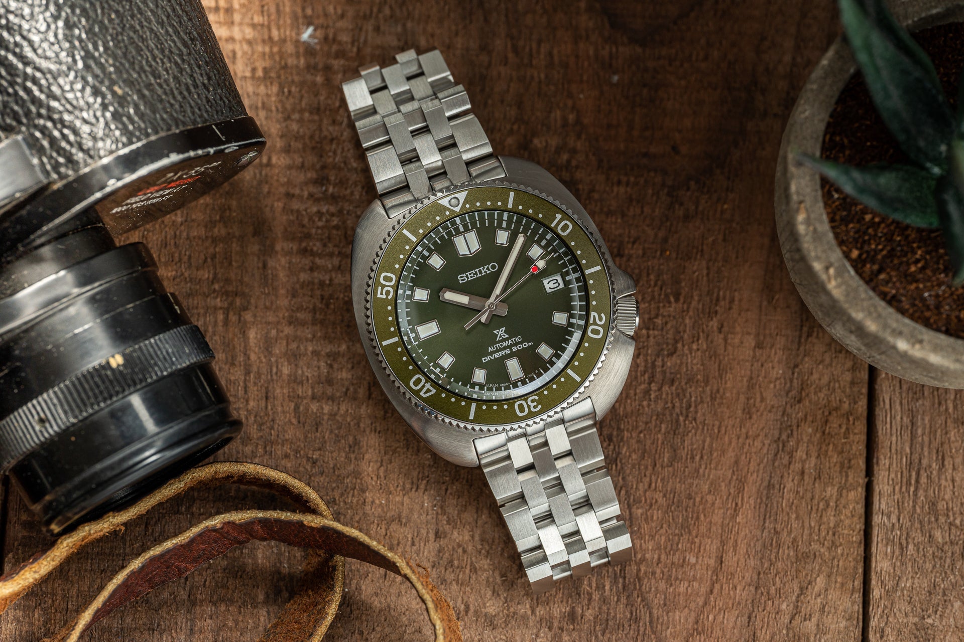 Seiko SPB15x Willard automatic diving watch with olive green dial, stainless steel bracelet, and rotating bezel on wooden surface