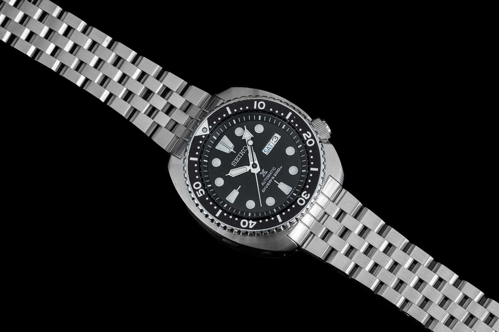 Seiko Super Engineer dive watch with black dial, rotating bezel, and stainless steel bracelet on black background