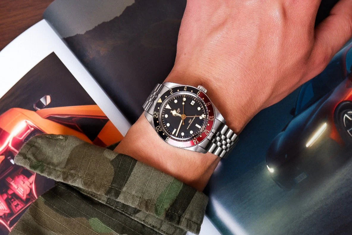 Men's stainless steel bracelet on wrist with luxury GMT diving watch, black dial red bezel