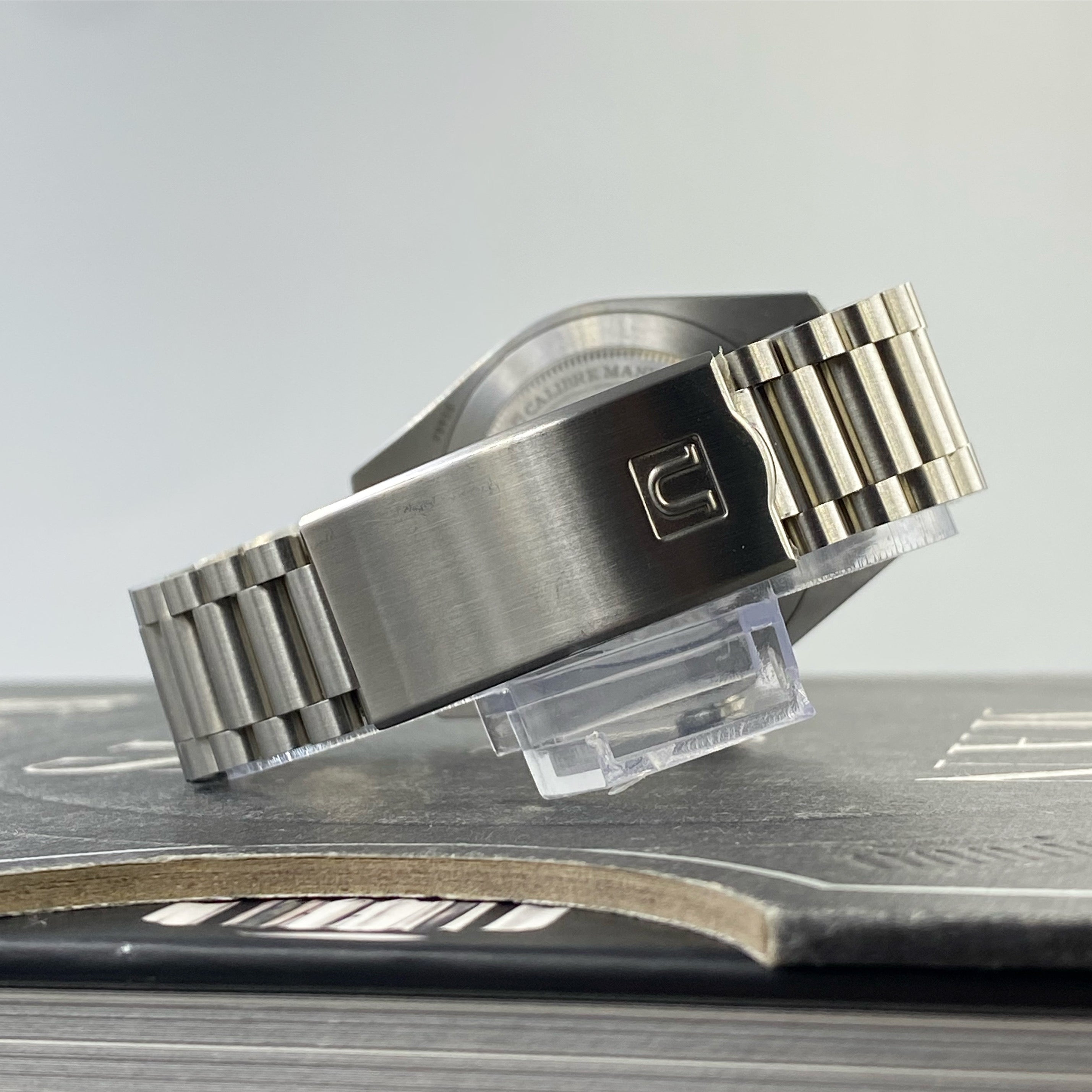 Stainless steel bracelet with solid links and clasp for Tudor Ranger 39 watch displayed on stand
