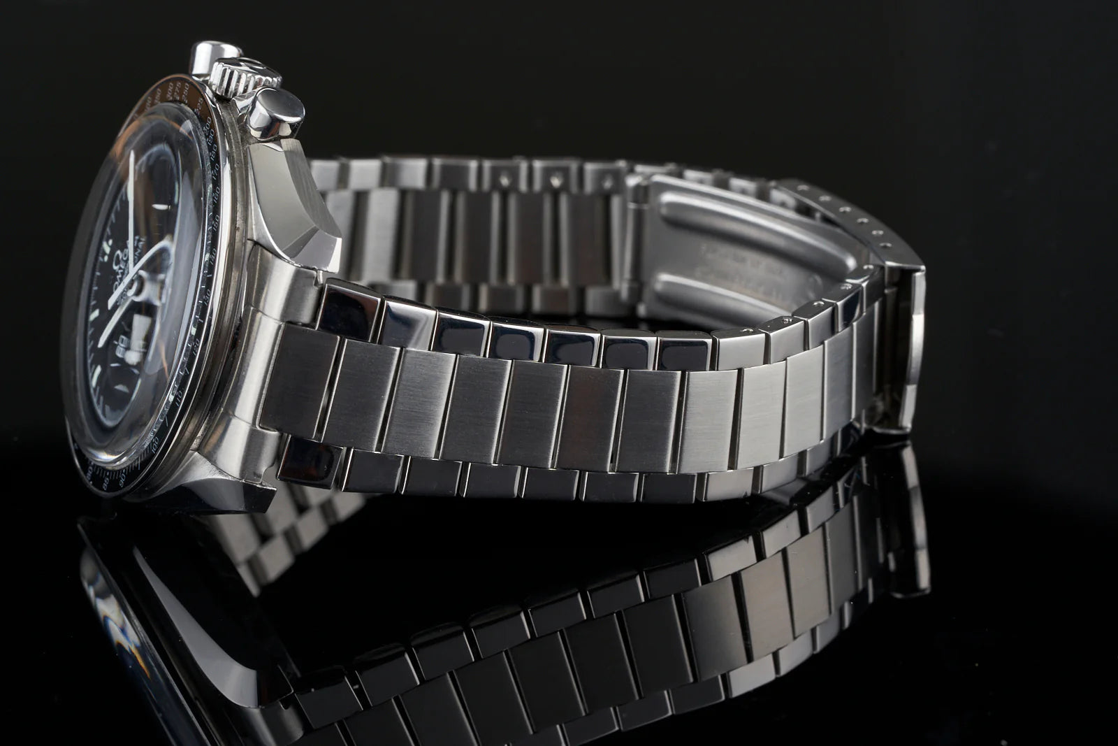 Stainless steel chronograph watch with flat link bracelet and dark dial on black background