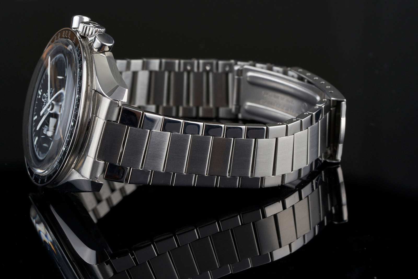 Stainless steel flat link bracelet for Omega Speedmaster watch with polished and brushed links on black background