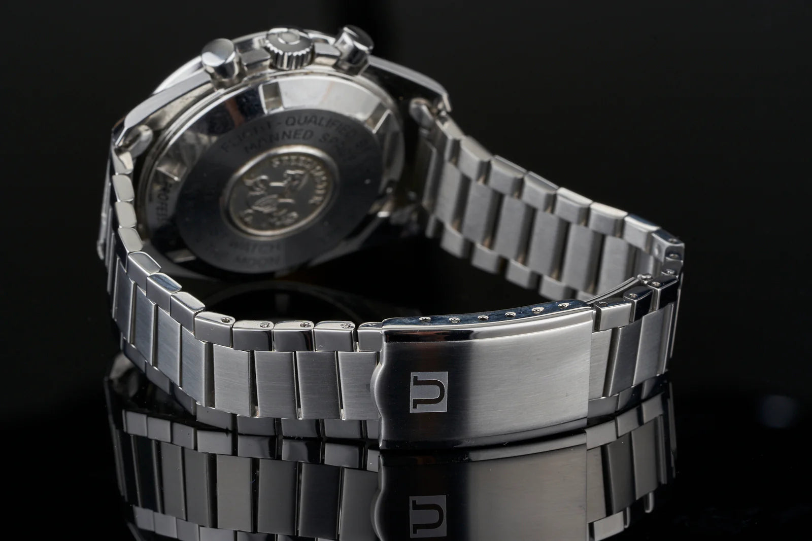 Stainless steel chronograph watch with flat link bracelet and military-style case back displayed on black background