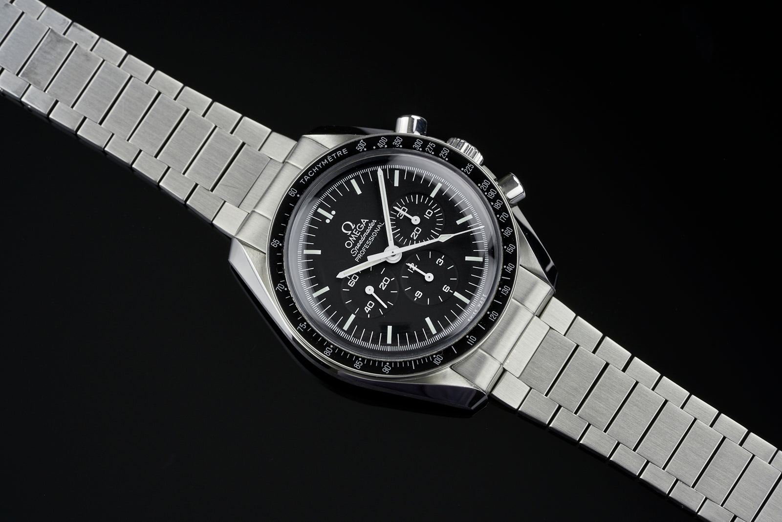 Stainless steel chronograph watch with black dial, tachymeter bezel, and flat link bracelet on black background