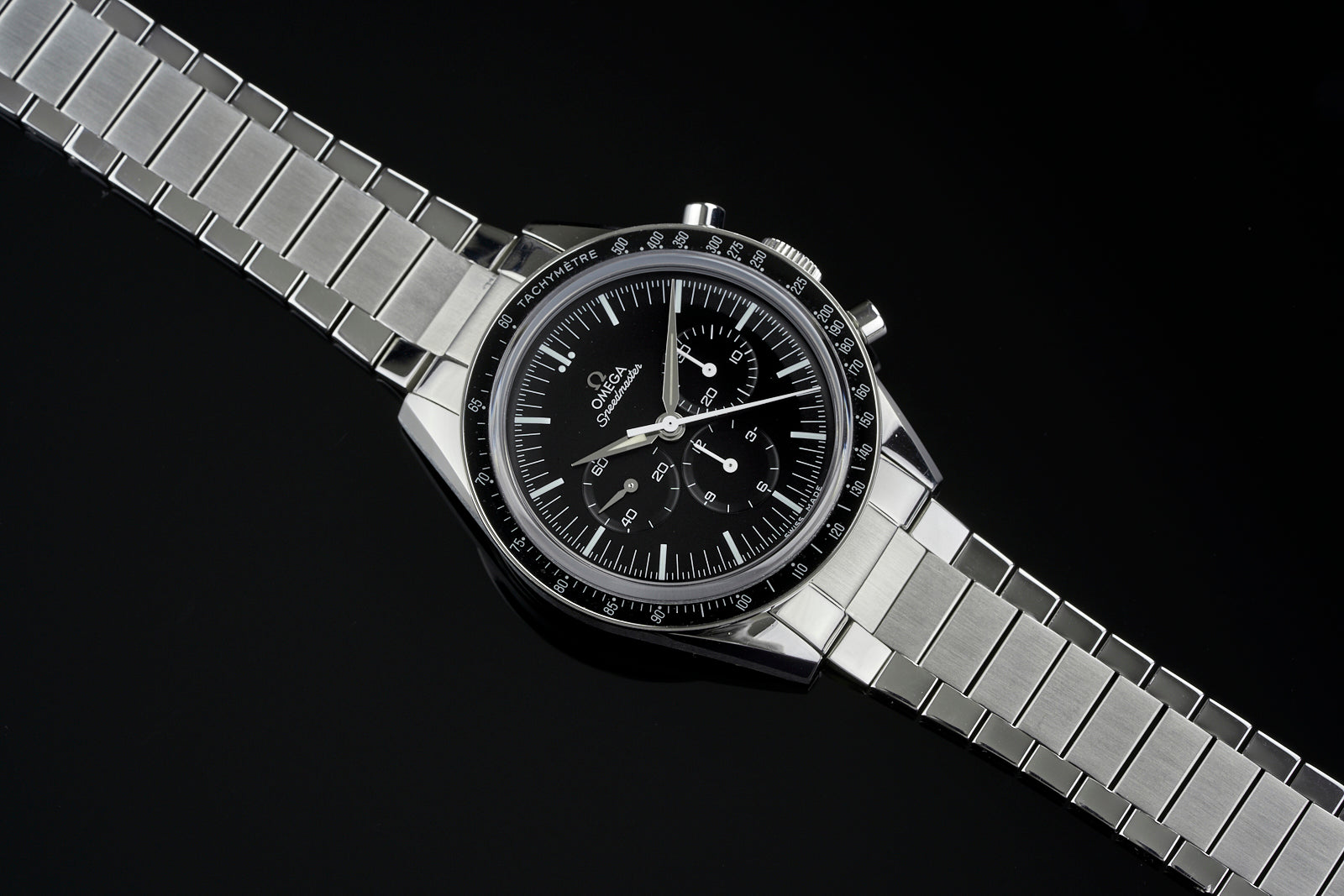 Omega Speedmaster chronograph watch with stainless steel flat link bracelet and black dial on black background