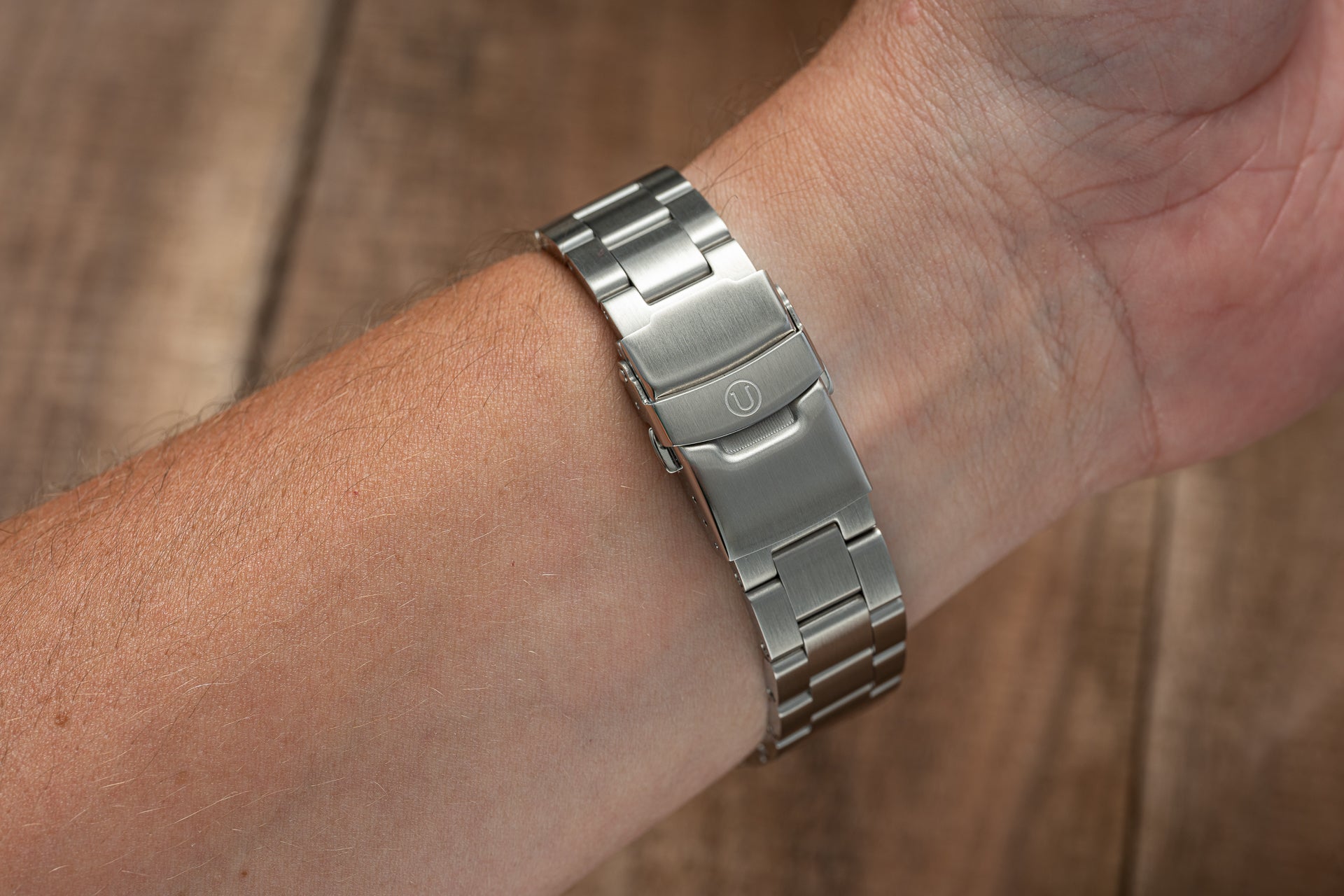 Stainless steel watch bracelet on wrist showing polished and brushed metal links with secure clasp closure