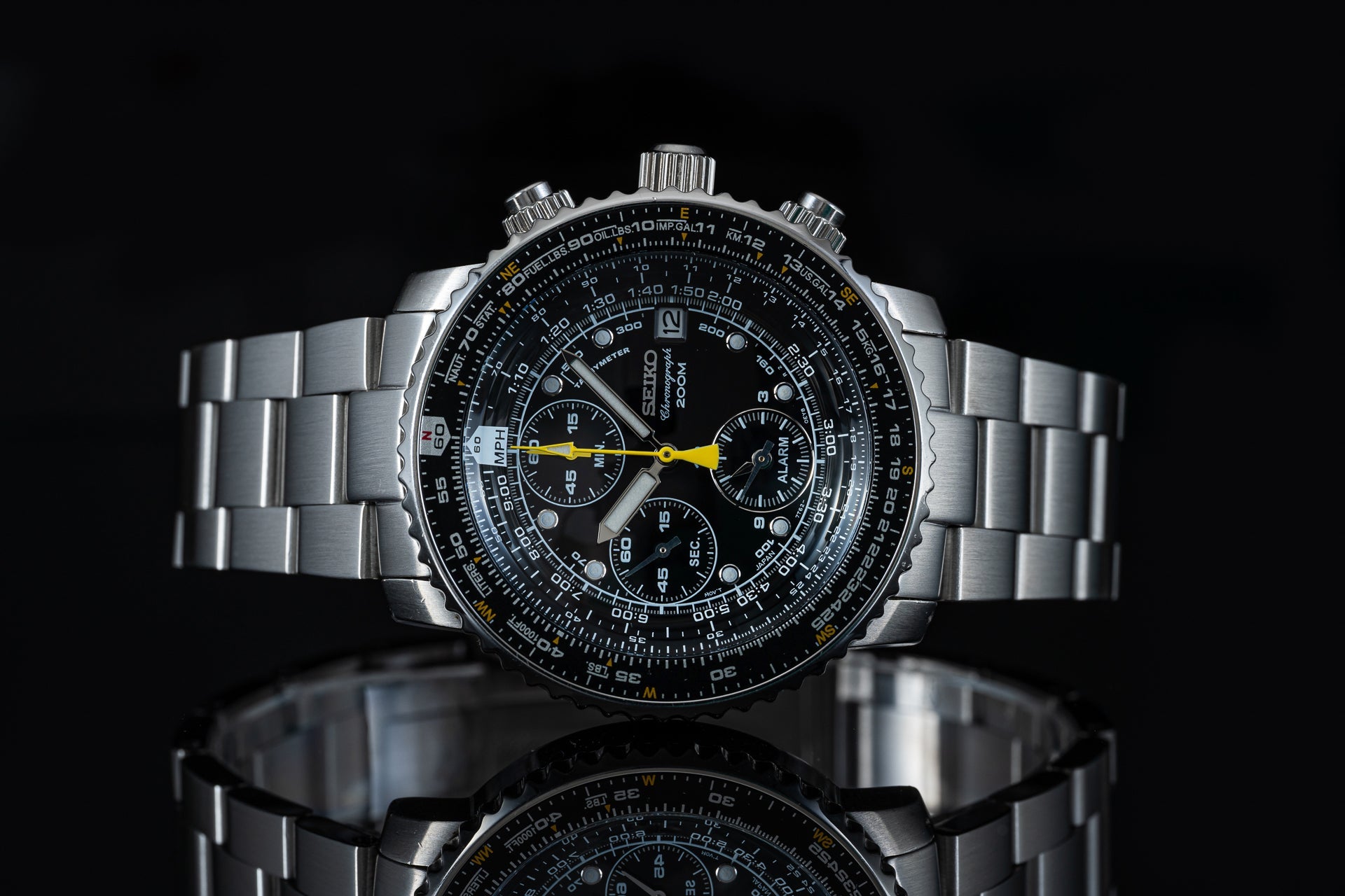 Seiko SNA411 Flightmaster stainless steel chronograph watch with black dial, yellow hands, and metal bracelet on black background
