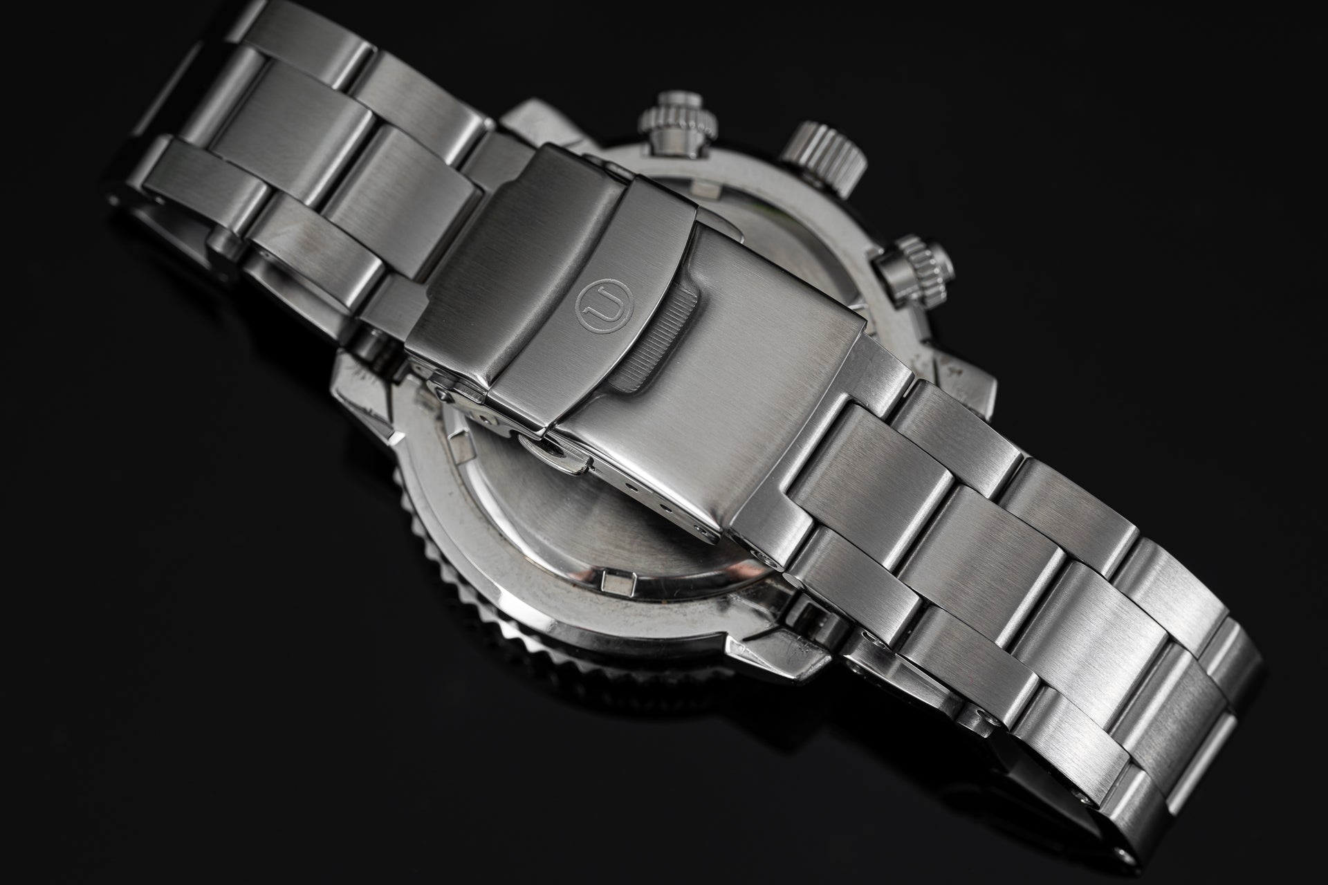 Stainless steel chronograph watch with metal bracelet, rotating bezel, and three subdials on black background