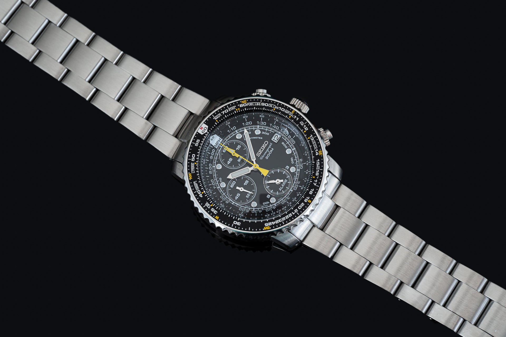 Seiko SNA411 Flightmaster chronograph watch with stainless steel bracelet, black dial, and yellow accents on black background
