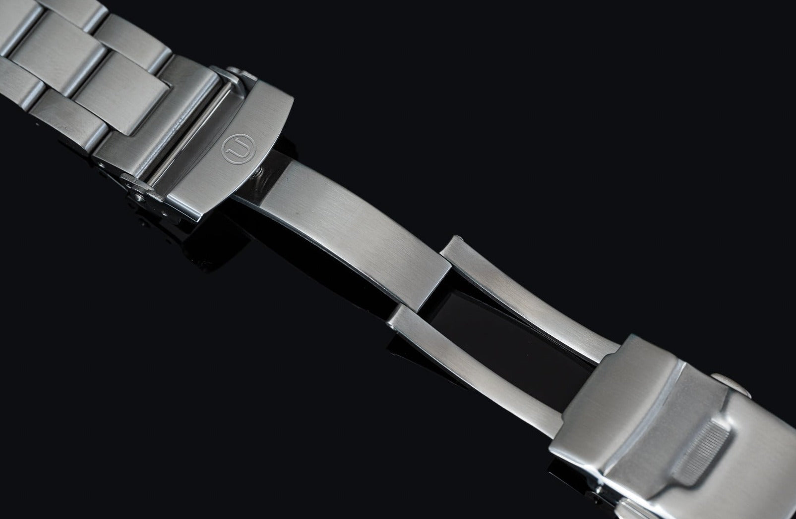Stainless steel military watch bracelet with adjustable links and secure clasp closure on black background