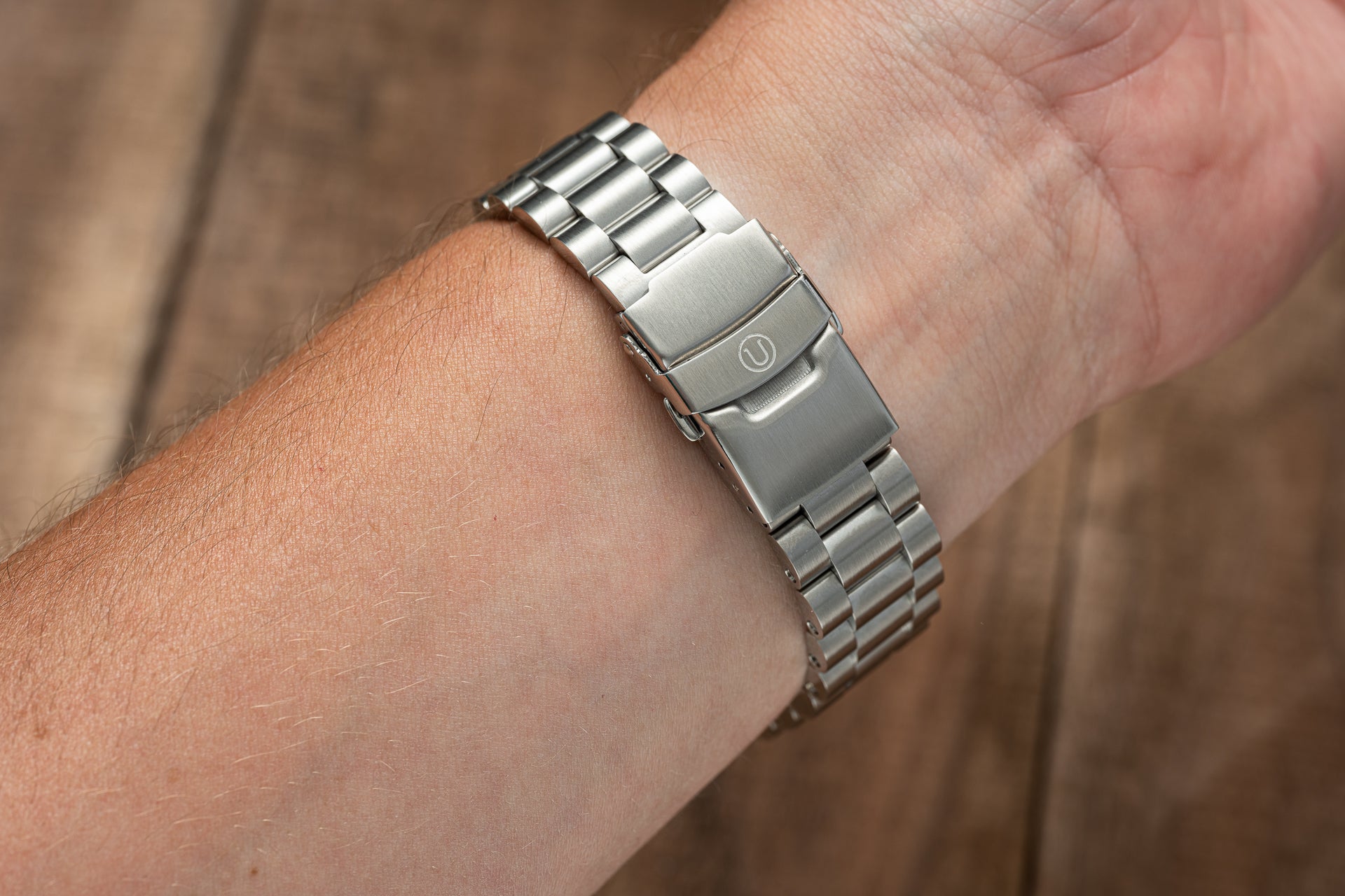 Stainless steel three-link bracelet on Seiko SNA411 Flightmaster watch worn on wrist, showing brushed metal finish and deployment clasp