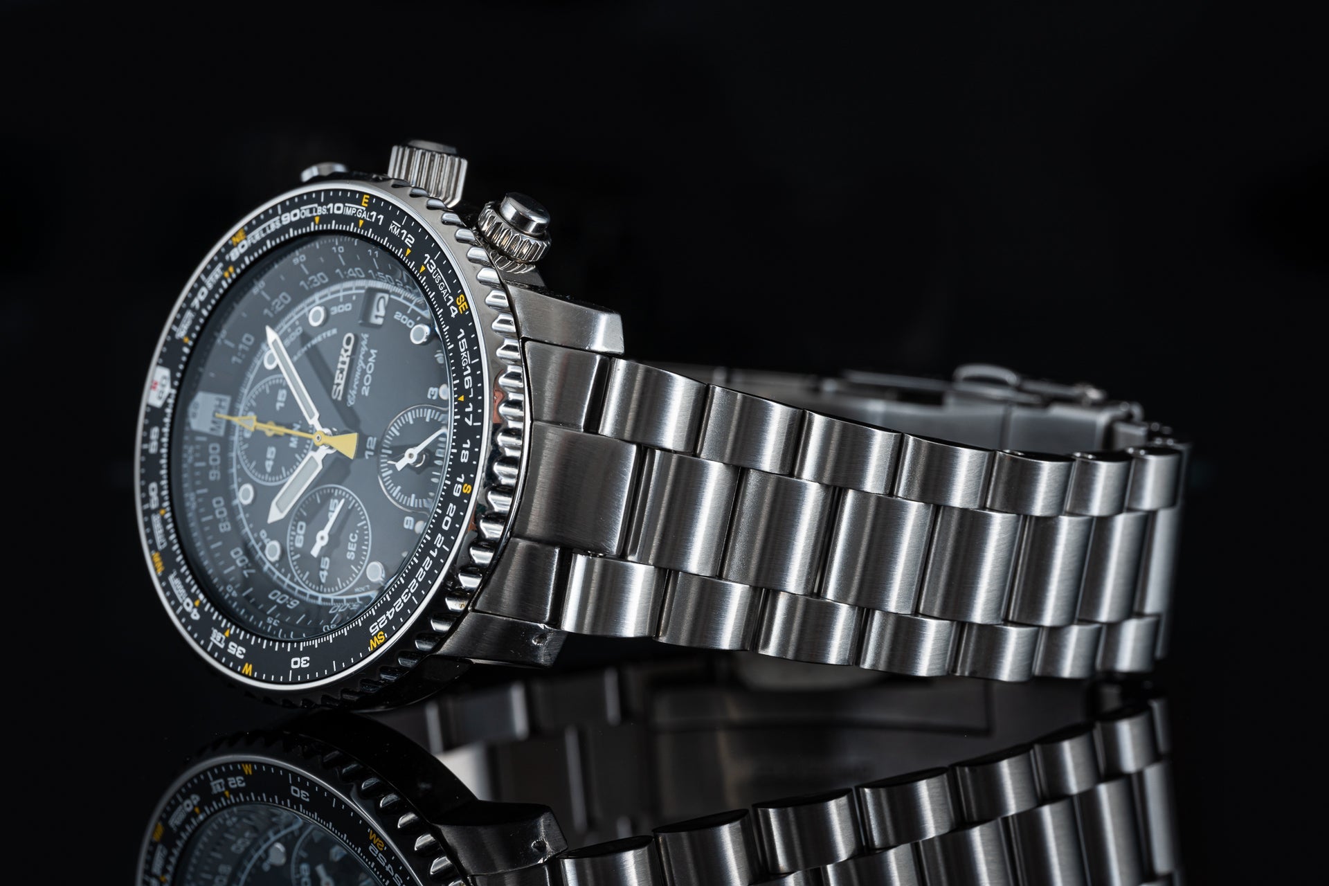 Seiko SNA411 Flightmaster chronograph watch with black dial, yellow accents, stainless steel bracelet on black background