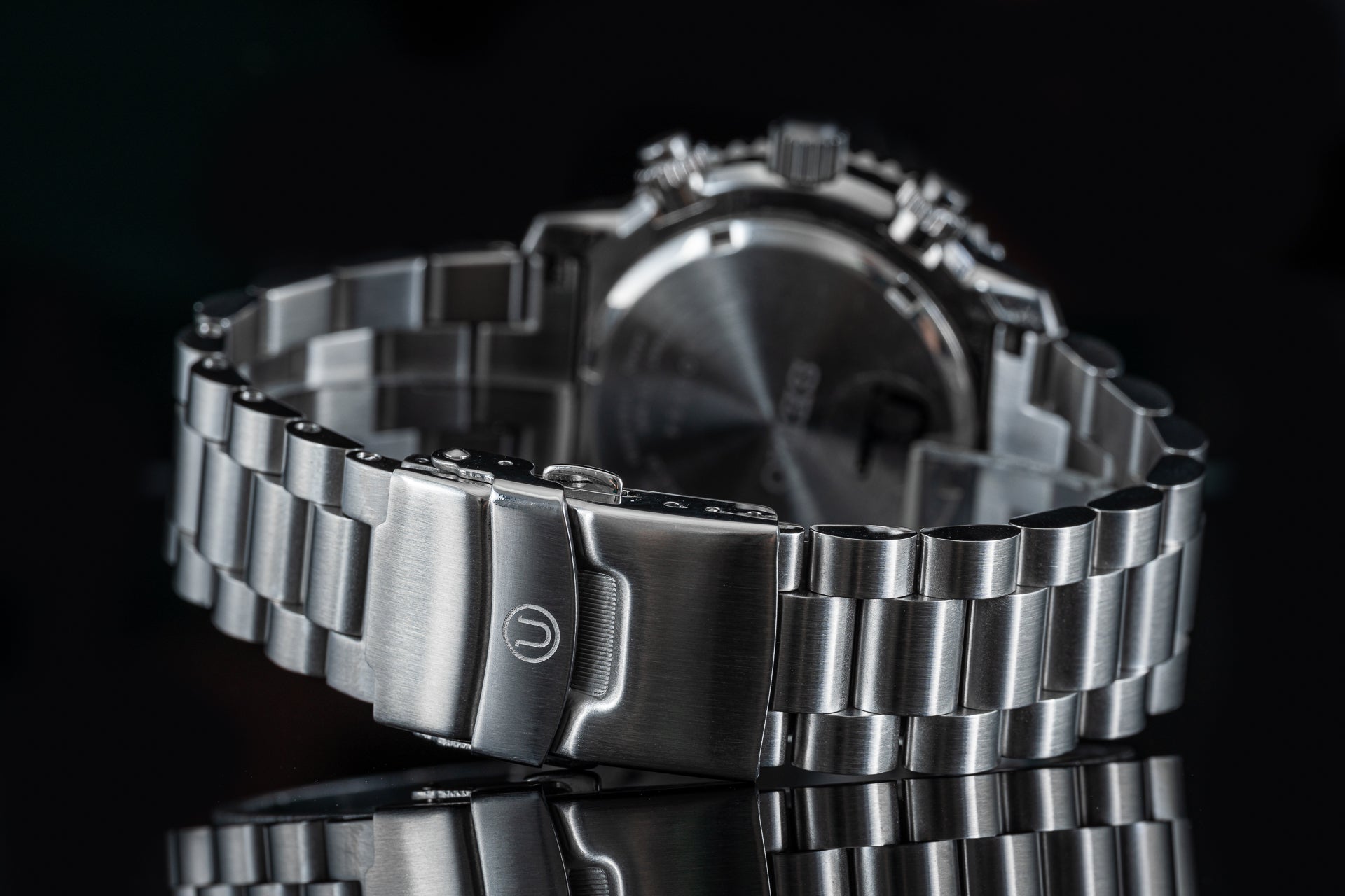 Stainless steel dive watch with linked metal bracelet and fold-over safety clasp on black background