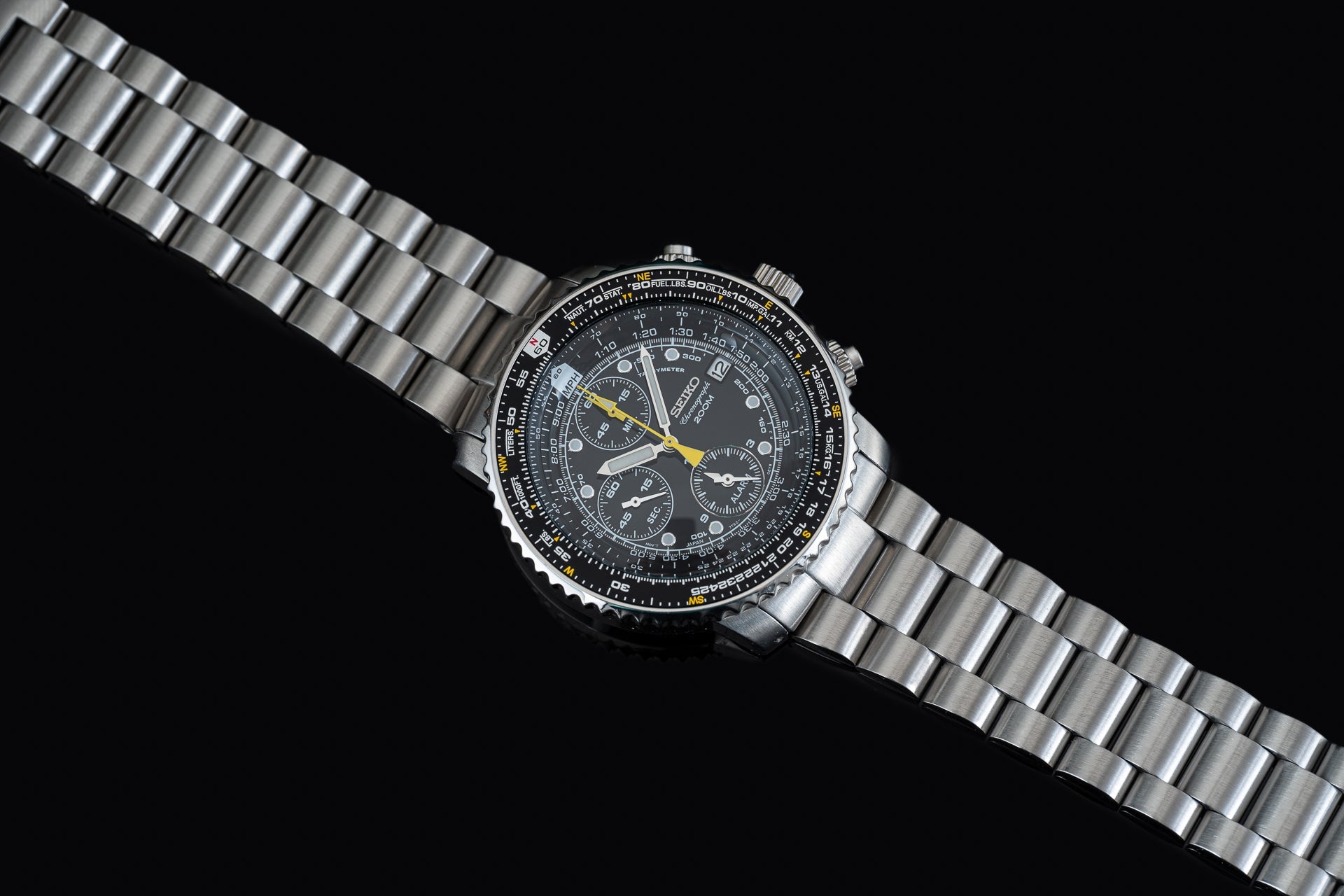Seiko SNA411 Flightmaster chronograph watch with black dial, yellow hands, stainless steel bracelet on black background