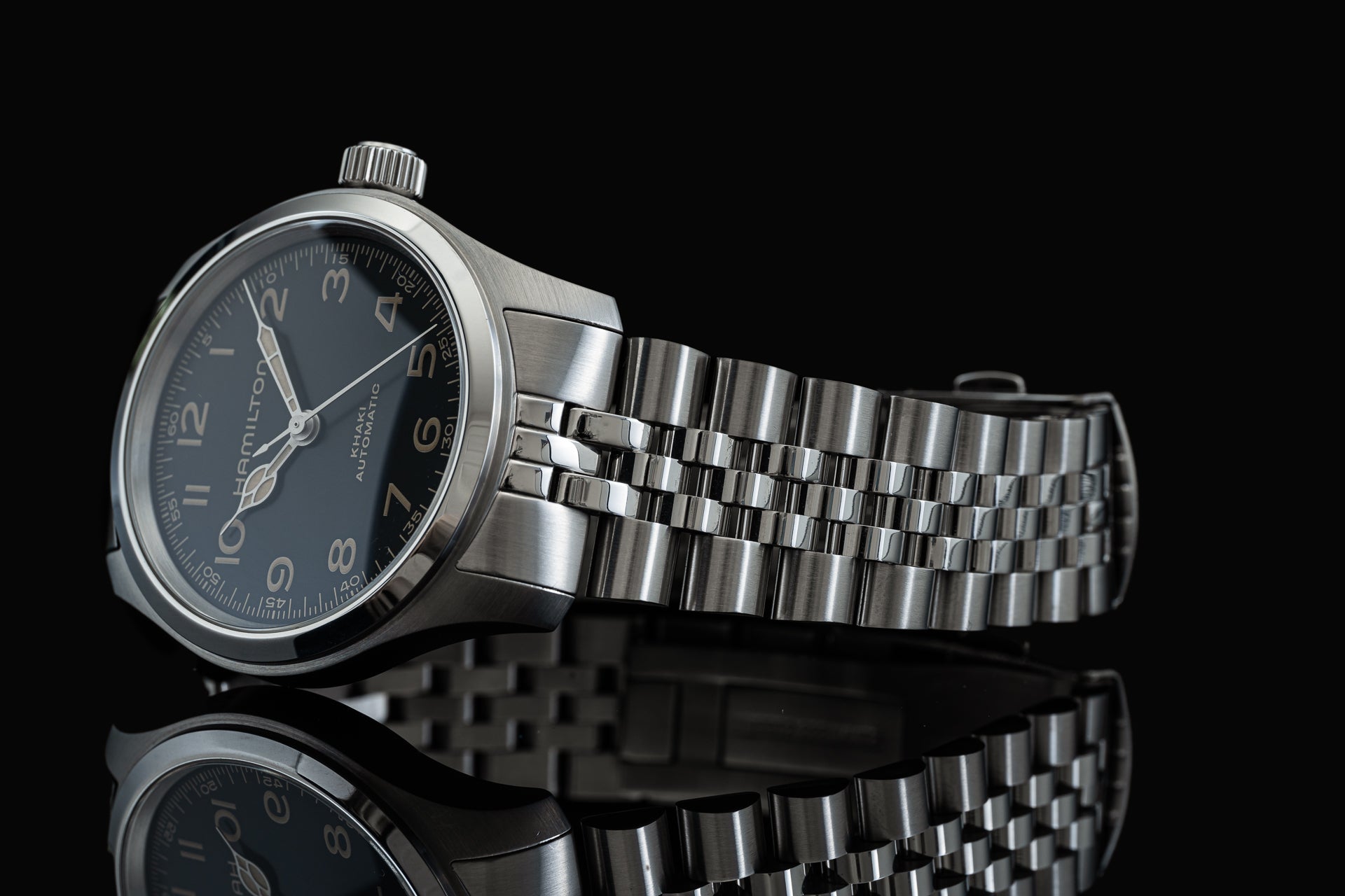 Stainless steel executive bracelet watch with black dial, Arabic numerals, and three-link metal band on black background